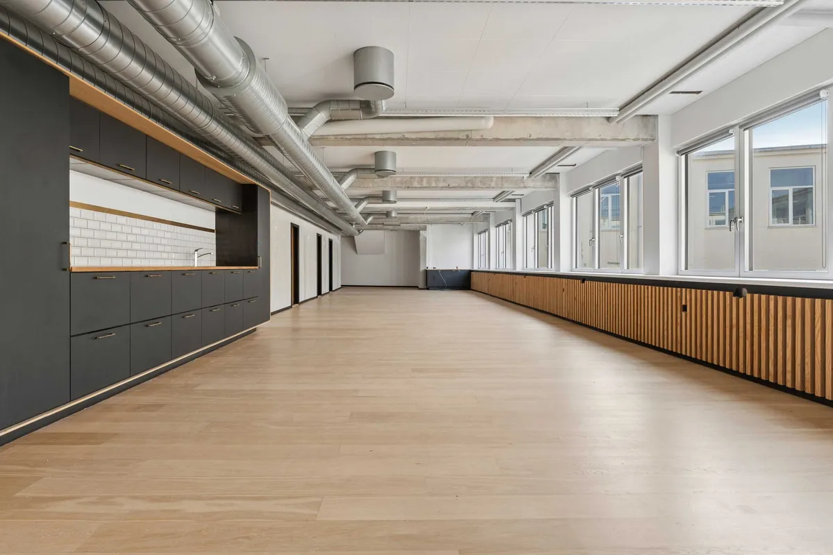 Lys moderne kontor med lyse lofter, høje vinduer og hårdt trægulv i en bygning med industriel karakter på Laplandsgade i København S