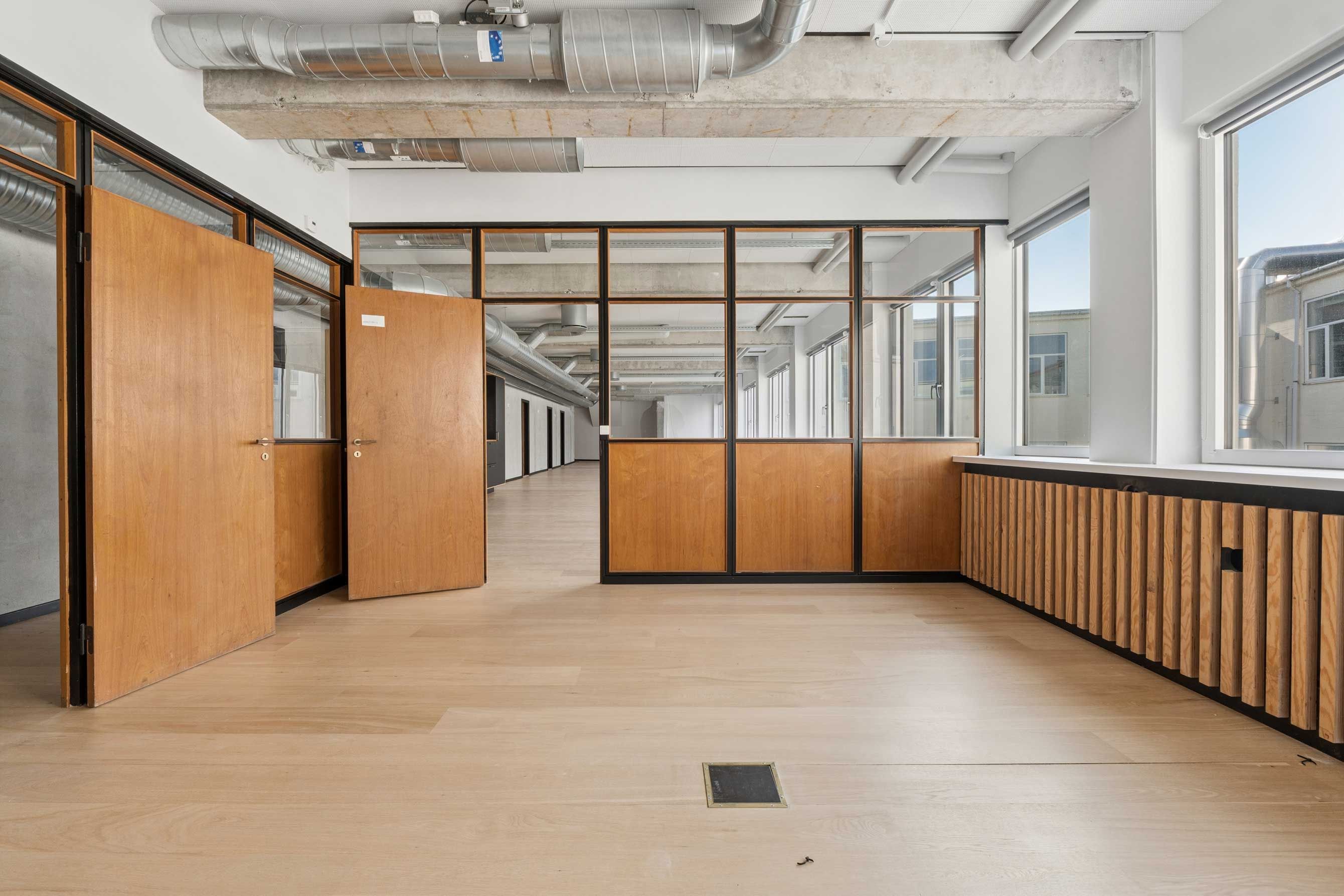 Indvendigt lejlighedskontor med højt til loftet og træpaneler, slanke vindueskarme og lyse gulve