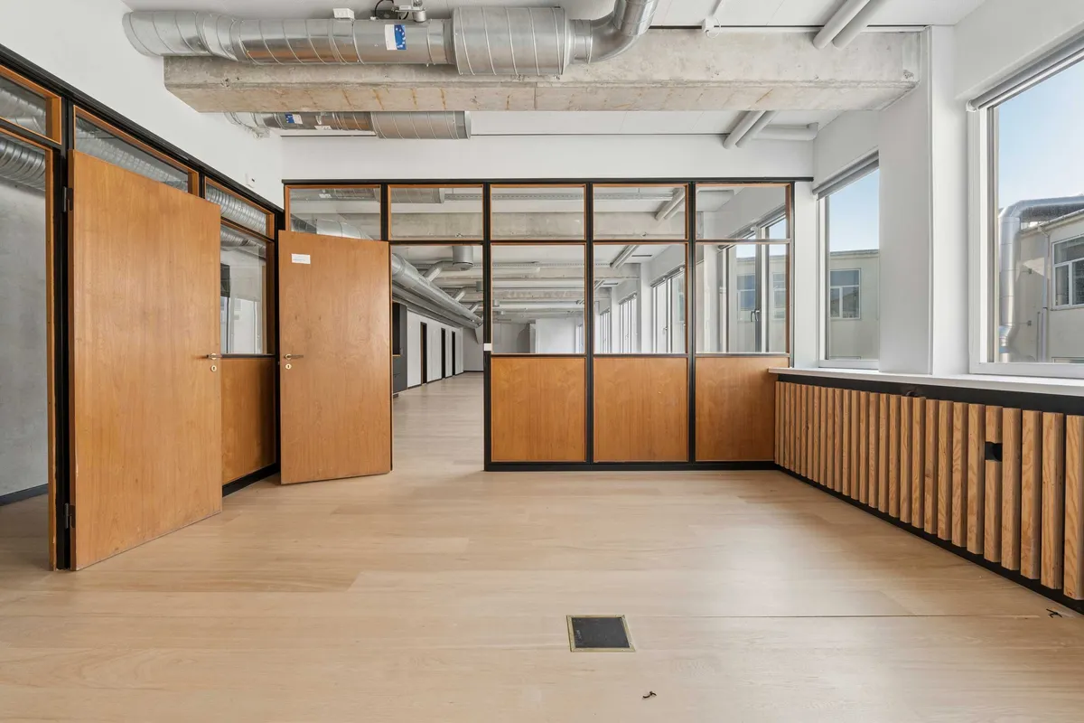 Indvendigt lejlighedskontor med højt til loftet og træpaneler, slanke vindueskarme og lyse gulve