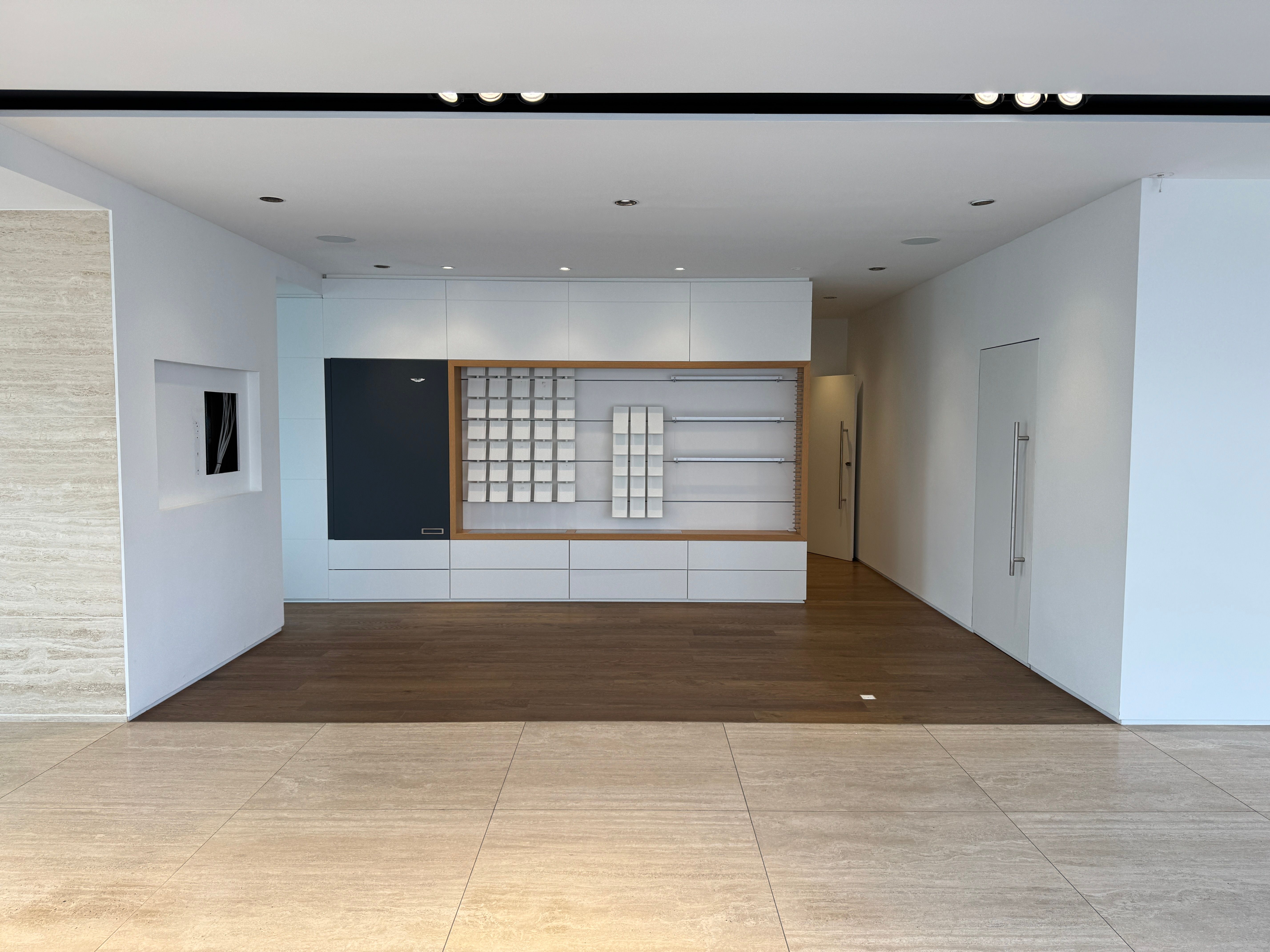 Eksklusivt showroom med højloft og moderne interiør. Hvidt loft og vægge med lysegult gulv. Vægmonteret højskab og høj kvalitet.