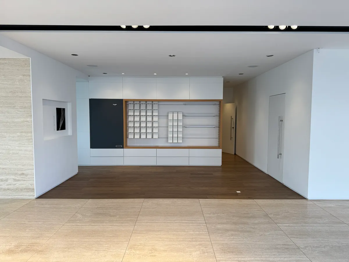 Eksklusivt showroom med højloft og moderne interiør. Hvidt loft og vægge med lysegult gulv. Vægmonteret højskab og høj kvalitet.