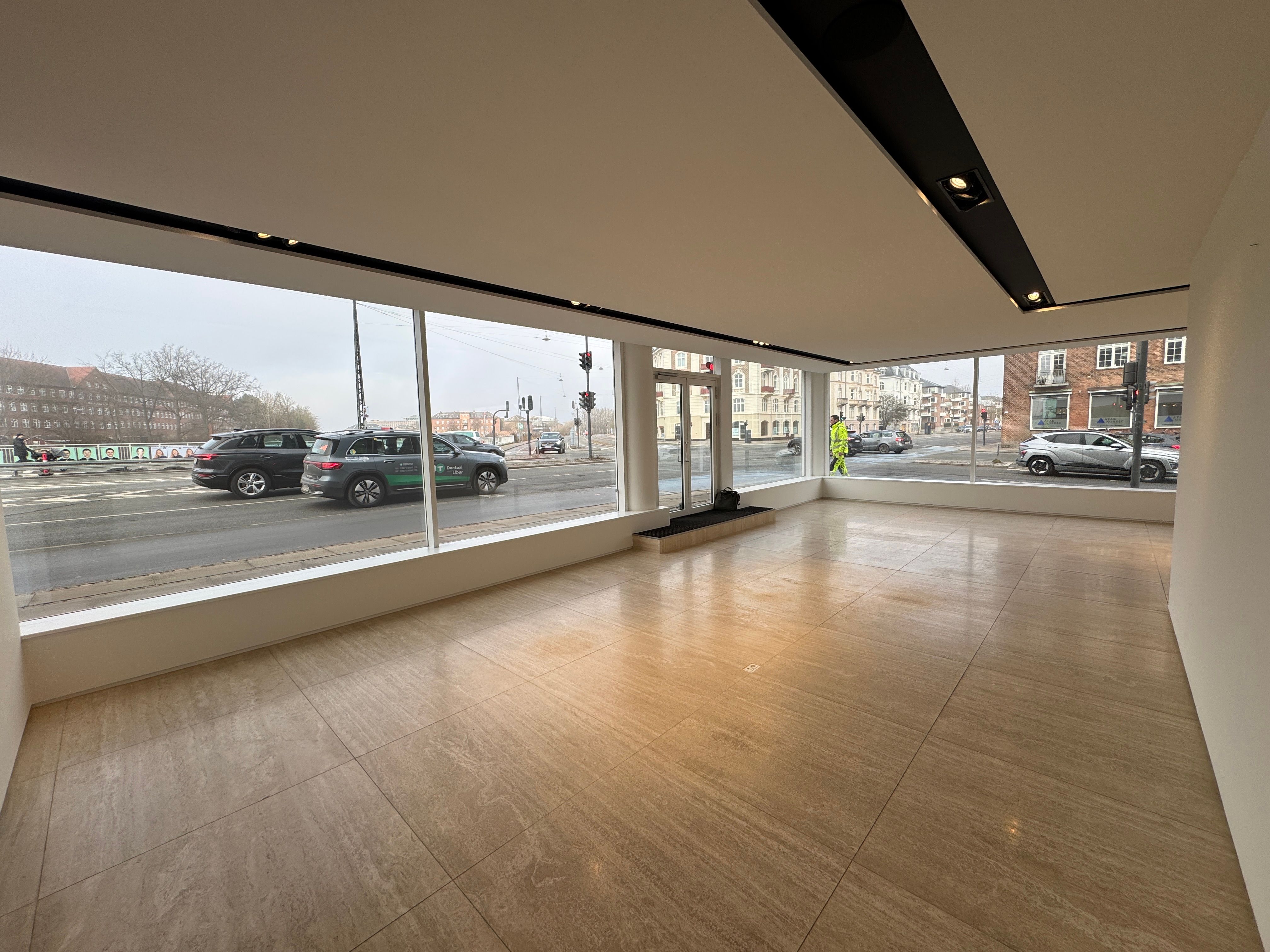 Tomme lokaler med gulv og store vinduer til leje i eksklusiv beliggenhed. Traffic og biler på vejen udenfor