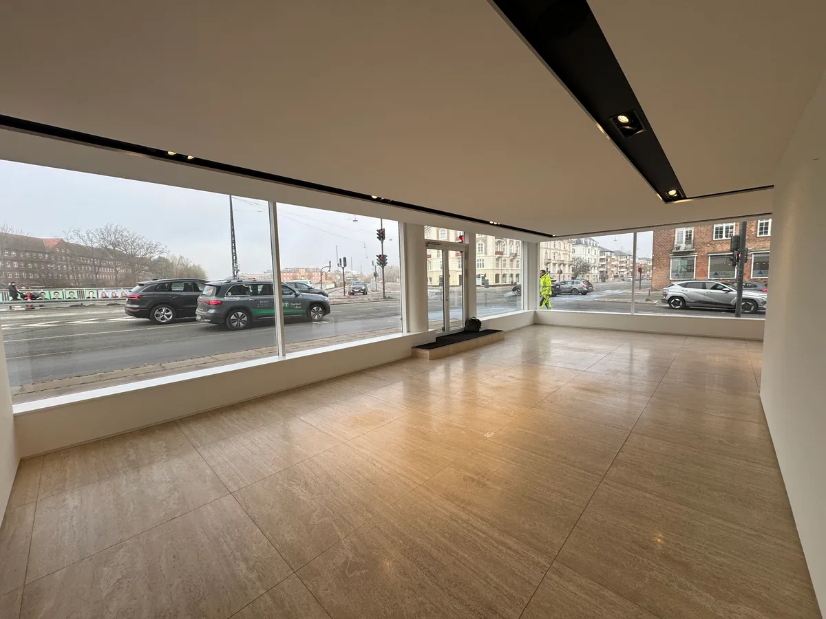 Tomme lokaler med gulv og store vinduer til leje i eksklusiv beliggenhed. Traffic og biler på vejen udenfor
