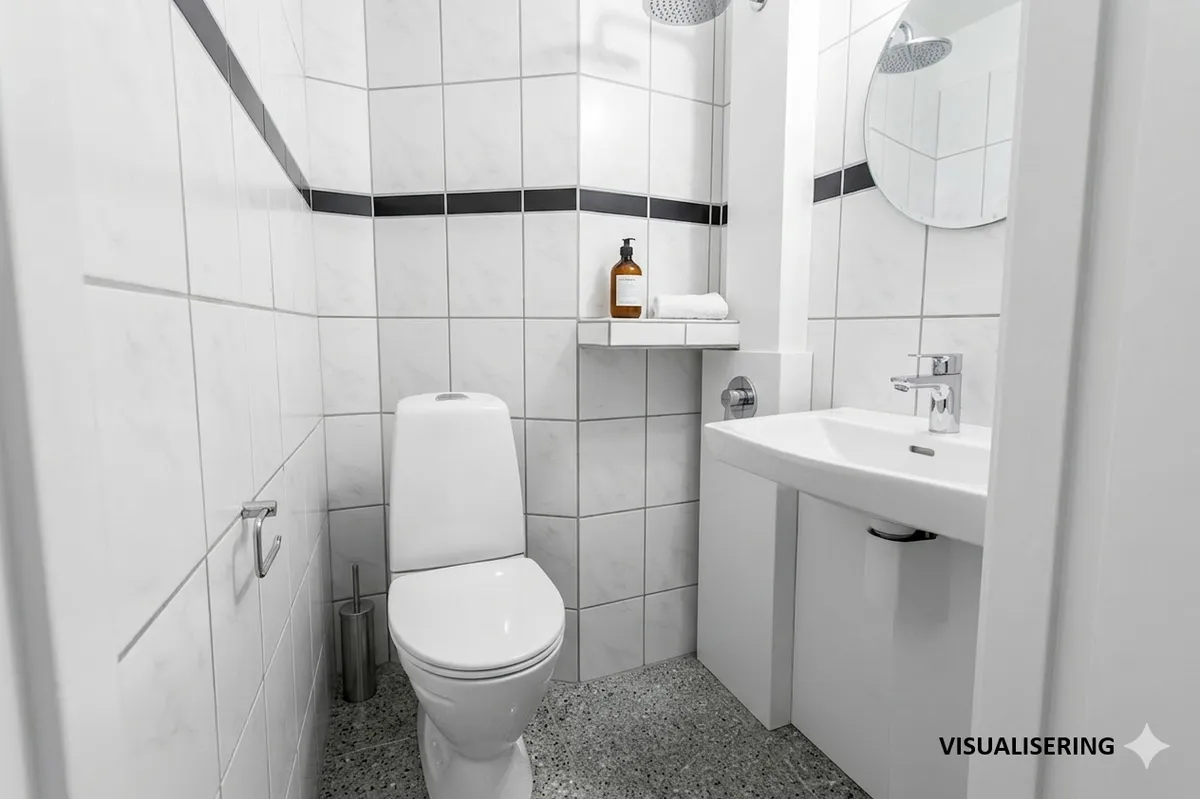 Et moderne badeværelse med hvide kakeloverflader og møbler, inklusiv en hvid toilet, en hvid vask og en spejl med indbygget lysekron.