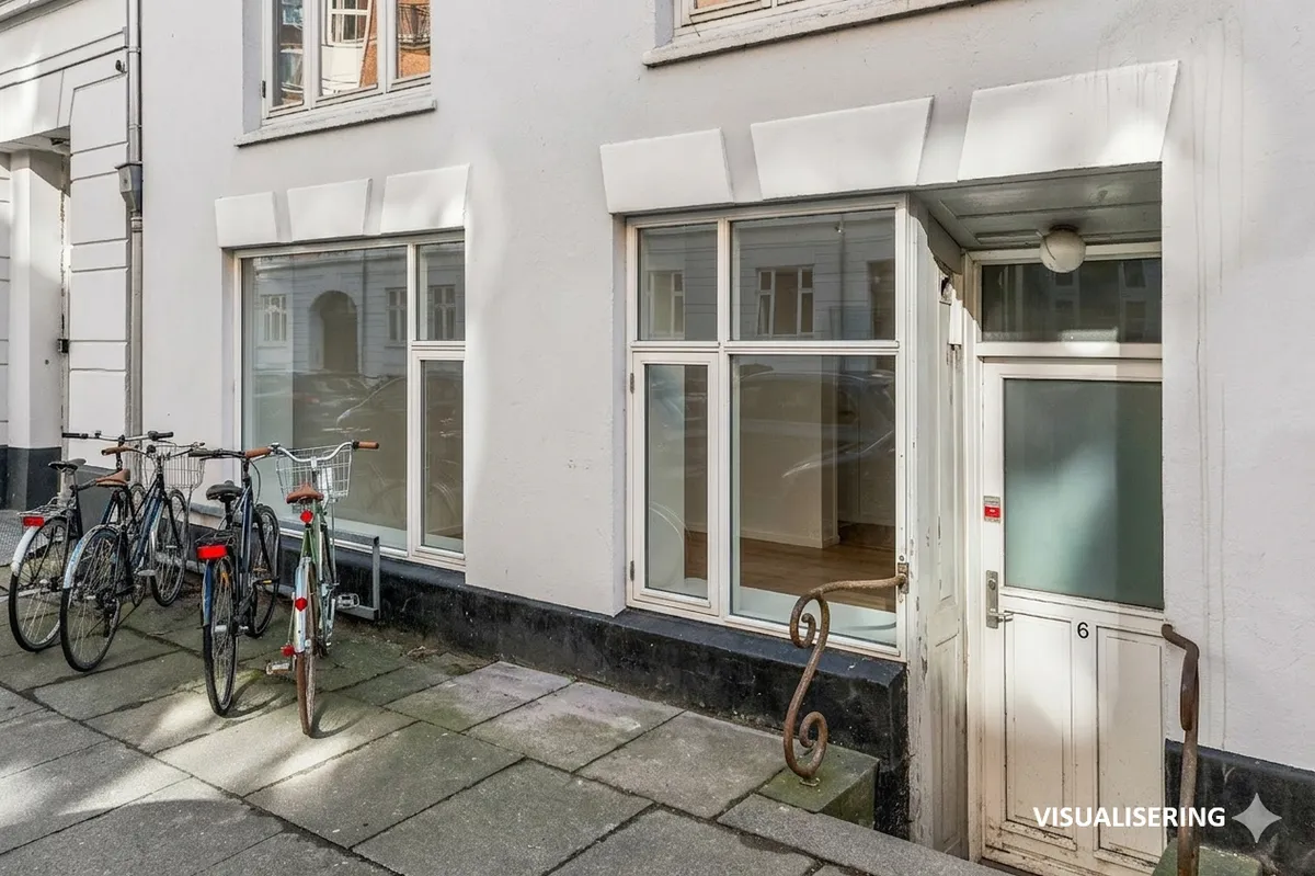 Butik til salg på Marstalsgade 6 med fire parkerede cykler udenfor og indgangsdør i træ med nummer 6 og lys.