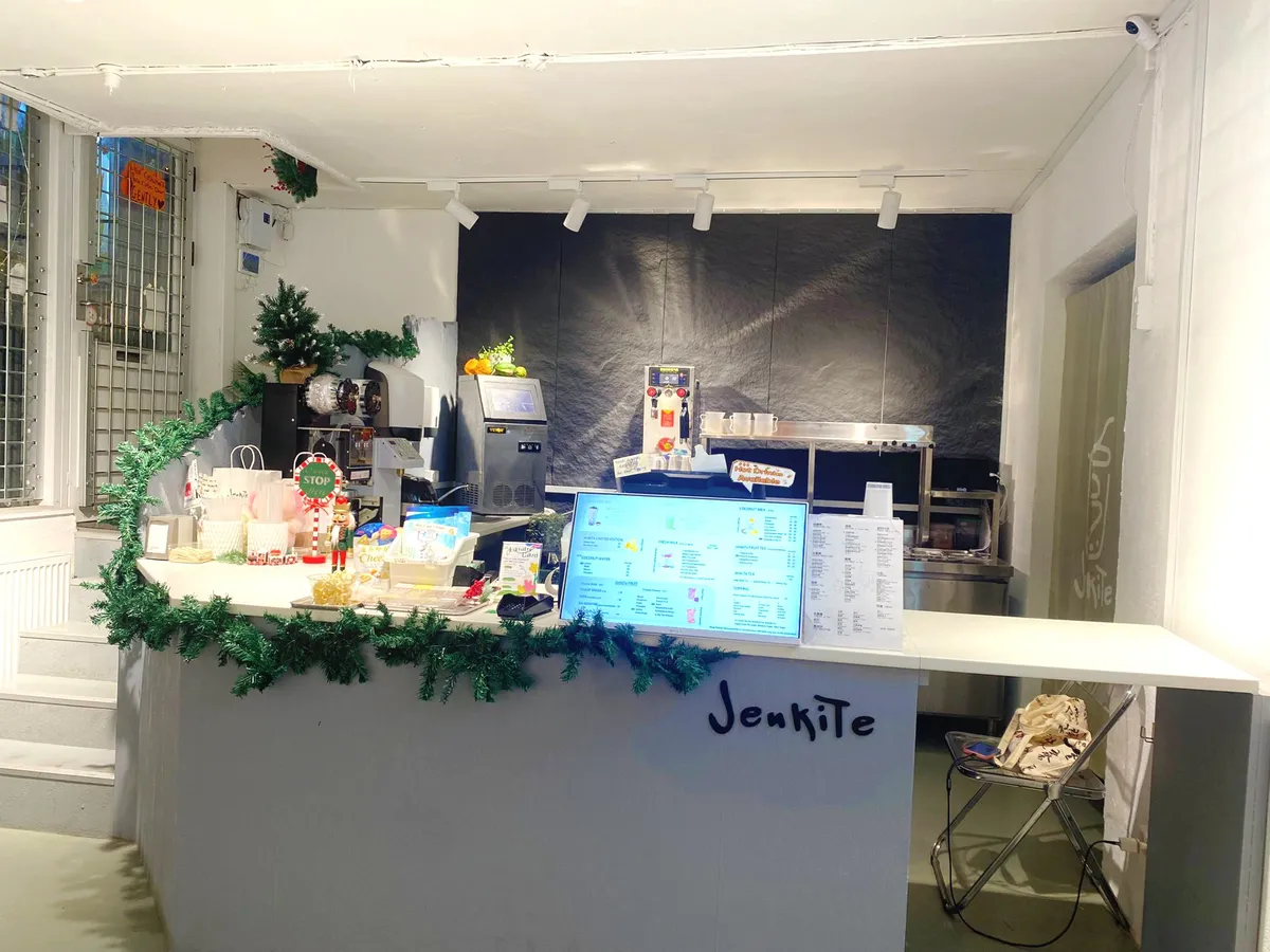 En bubble tea butik med en særprægget facade og en sømløs kundeoplevelse. En arbejdsbord med menukort, en skrivemaskine og en juletræsdekoration.