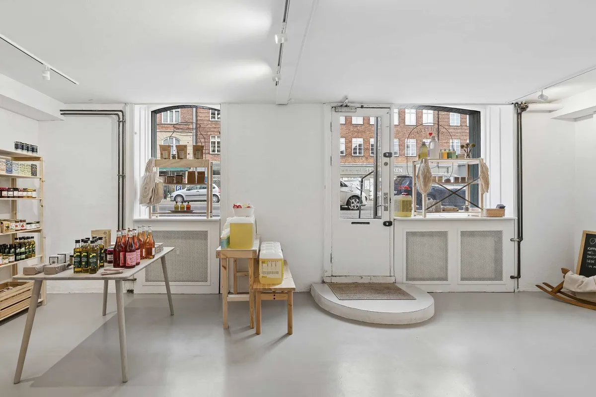 Køkkenbord med flasker og beholdere og en vindue med udsigt til gadebilten og biler parkeret udenfor.