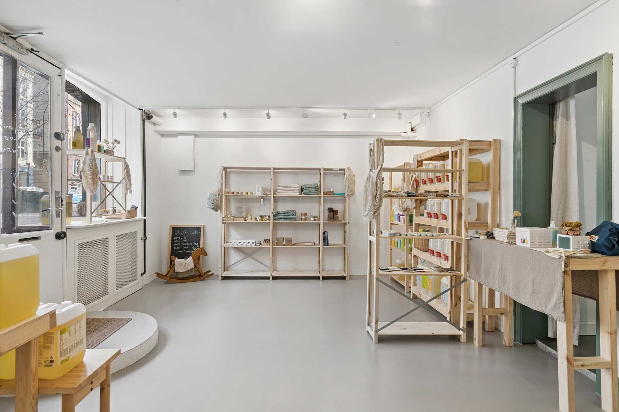 En møbleret og ren forretning med store vinduer og et hvidt loft og vægge