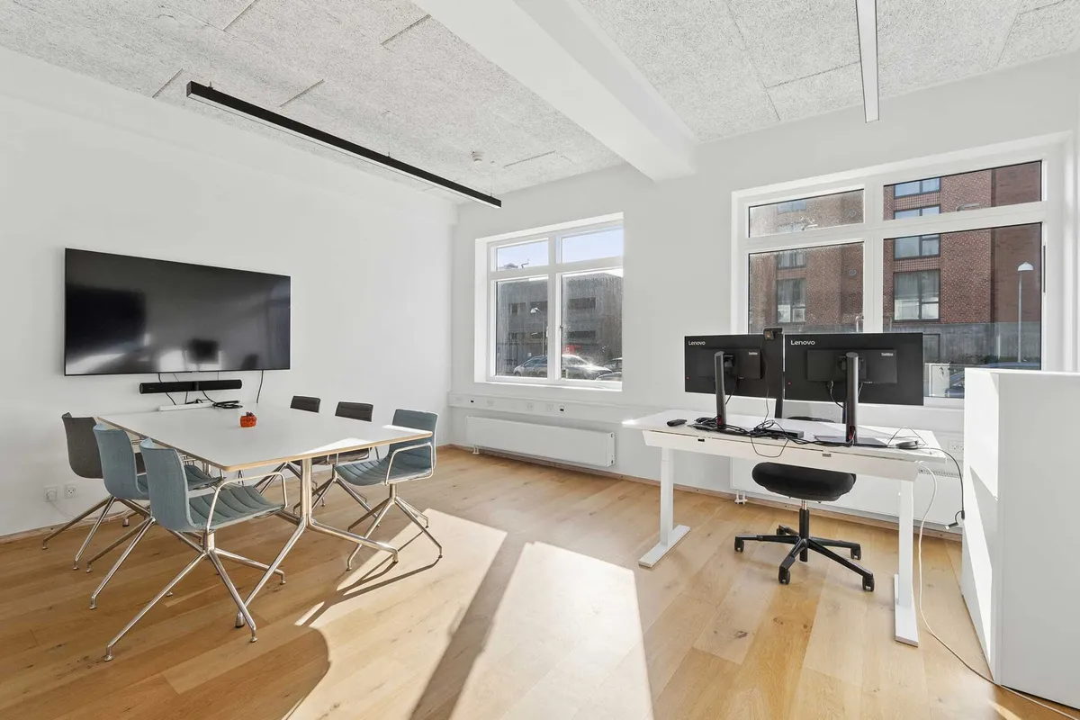 Kontorlokaler med højt til loftet og moderne møbler og teknologi til møder og konferencer i en stilfuld indretning