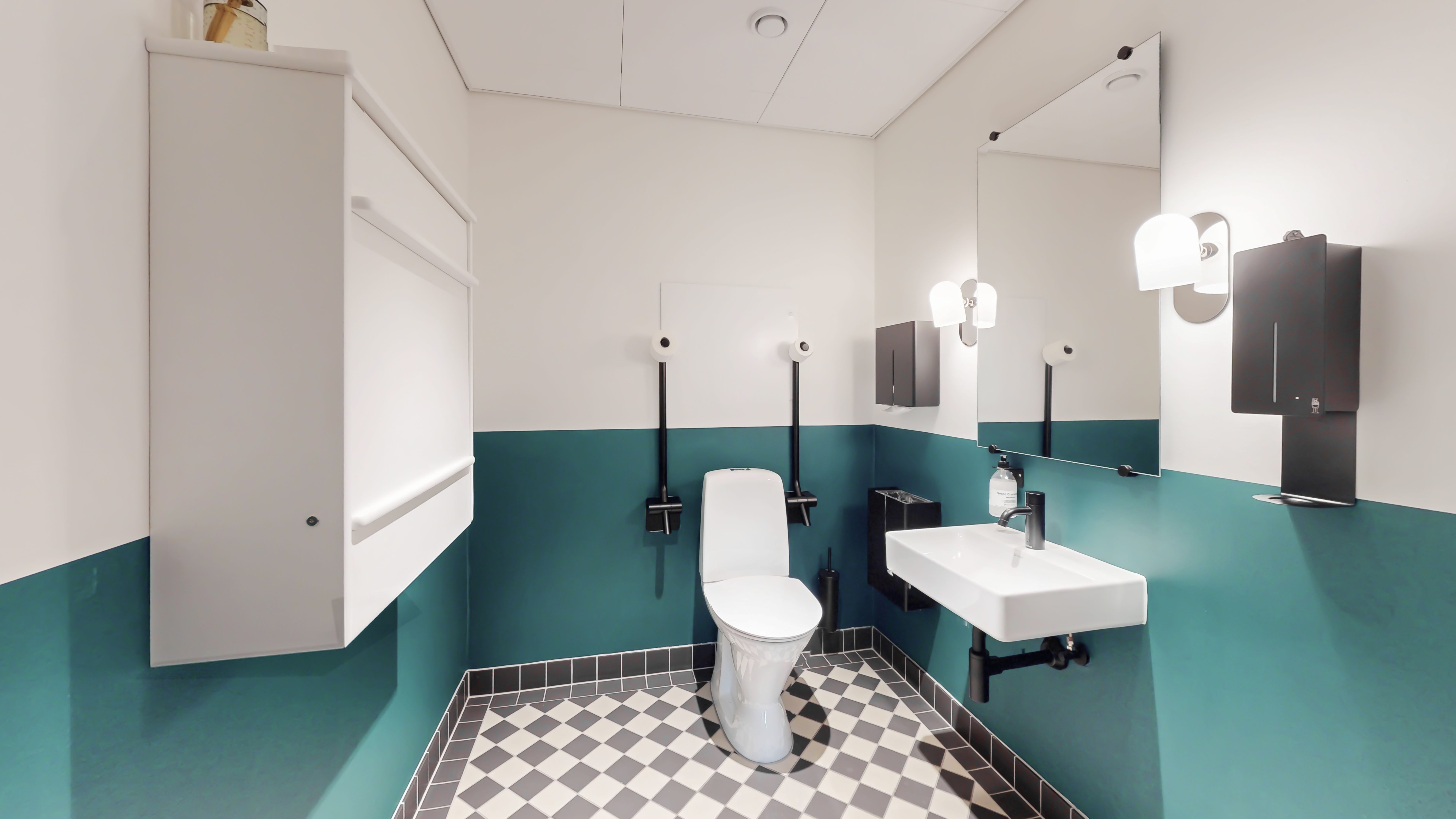 En moderne toiletrum med hvidt toilet og hvidt vask. Murene er malet turkis og hvidt. Der er lysekroner og toiletpapir i rummet. Der er gulvbelægning med sort og hvide firkanter.