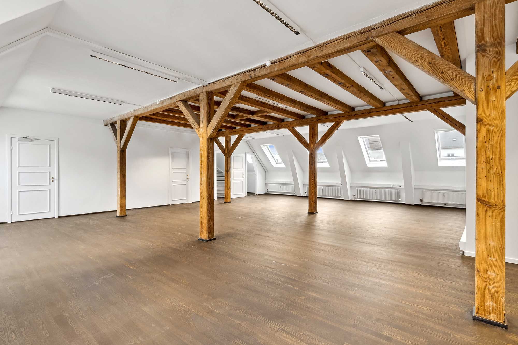 Kontorlokaler med træbjælker og lysegulve, højt til loftet, vinduer og hvide vægge. Sted: Toldbodgade 12, 3., København K