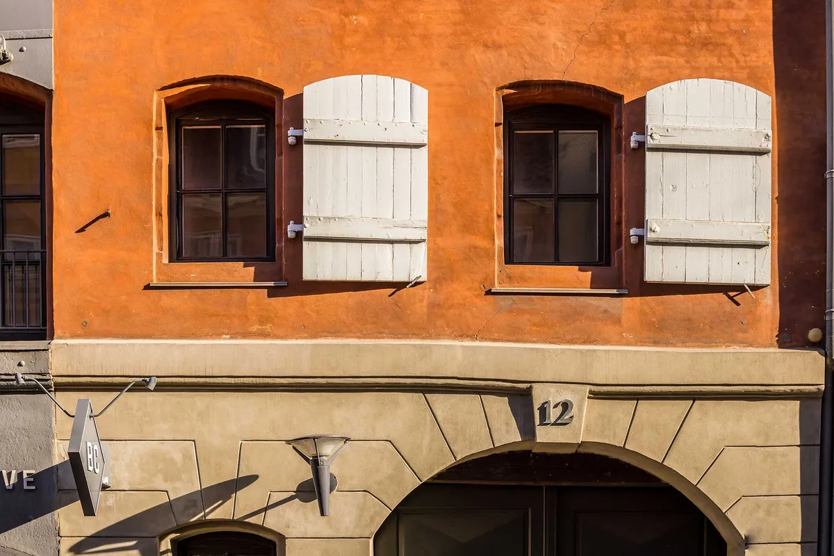 Kontorlokaler til leje på Toldbodgade 12. Bygningen er renoveret og malet i orange og beige. Kontorlokalerne har hvide vinduer og lysekroner.