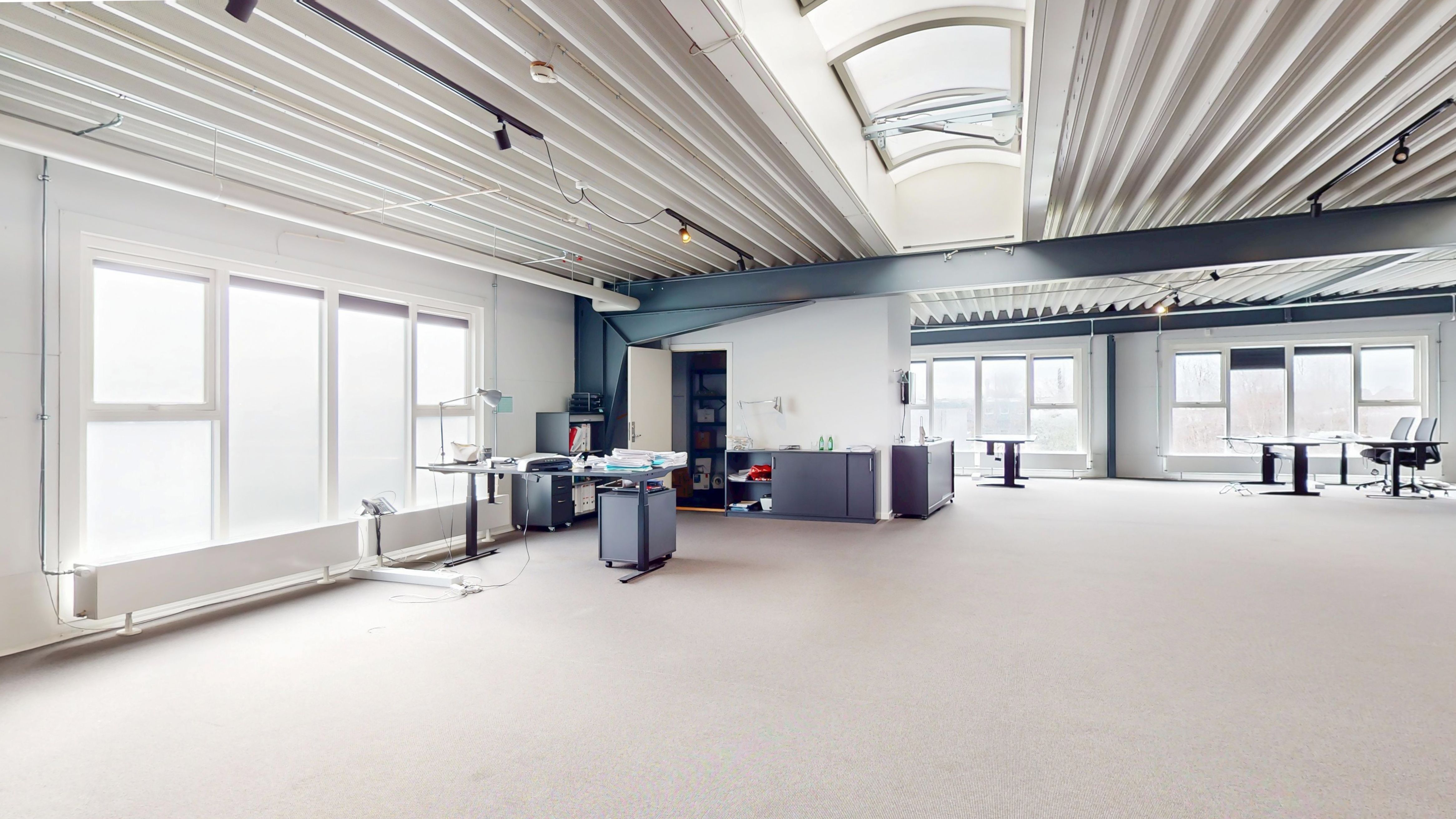 Store kontorrum med store vinduer og lyse lofter. Væsentligt meget plads til flere skriveborde og udstillingsområder. Minimalistisk indretning med moderne møbler og teknologi.