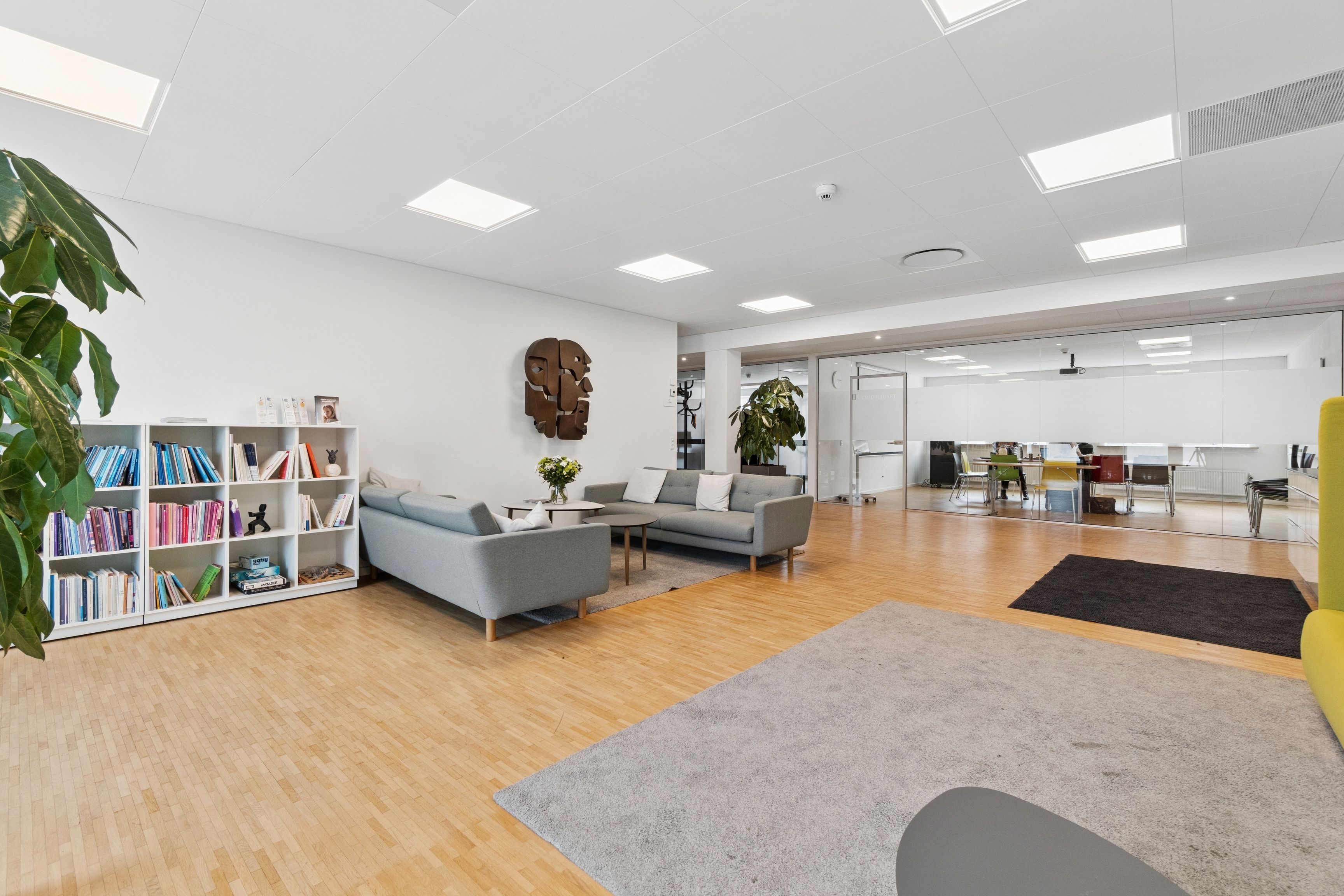Kontorlokaler med moderne indretning, hvidt loft, lysegulve og flere møbler samt sofaer, bibliotek og skrivebordsbord