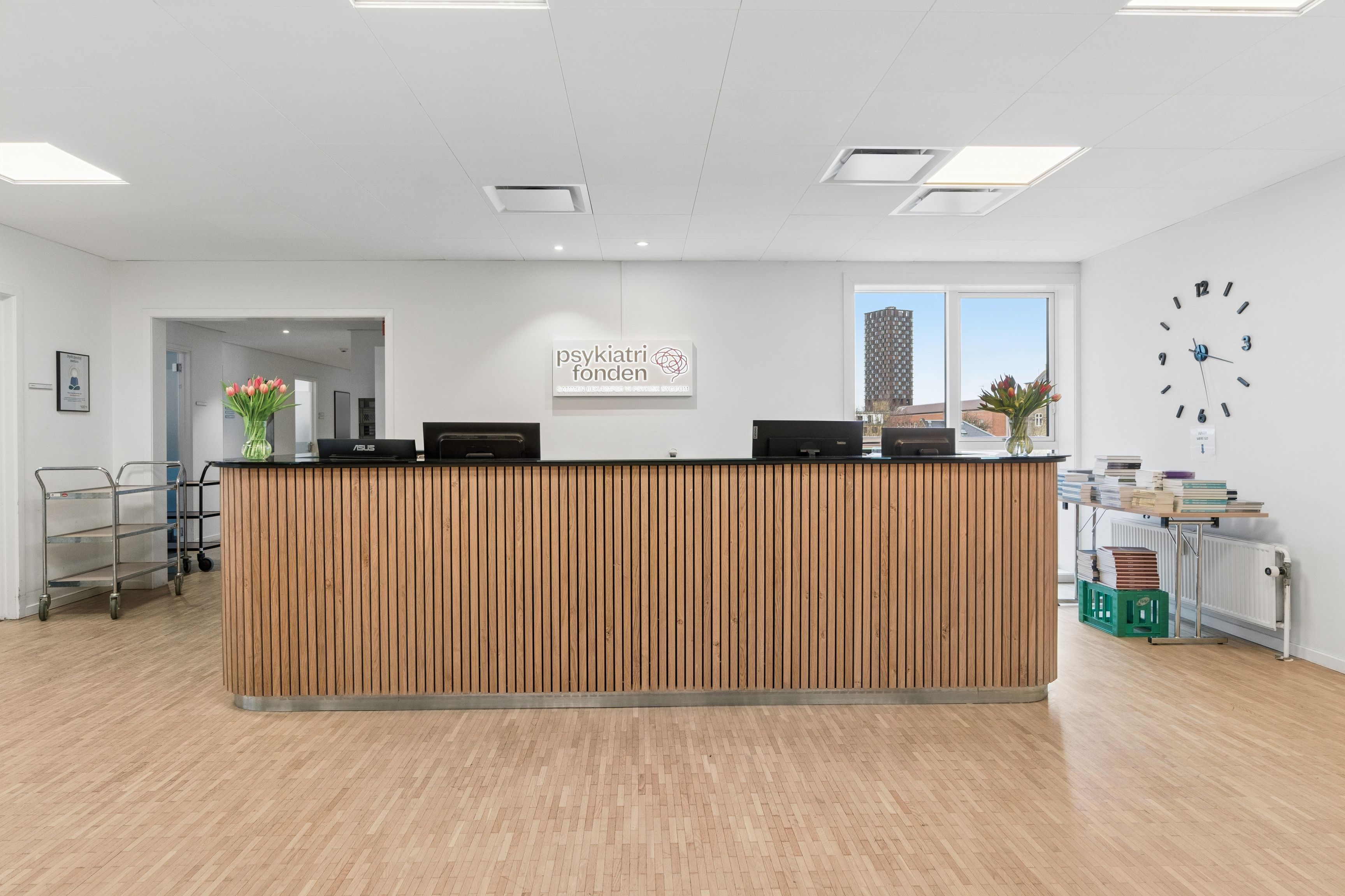 Moderne og veludstyret kontor med møbler og teknik. Indkøb af computere, skrivebord og køkkenudstyr. Blomster og ure i lyse og ryddige lokaler.