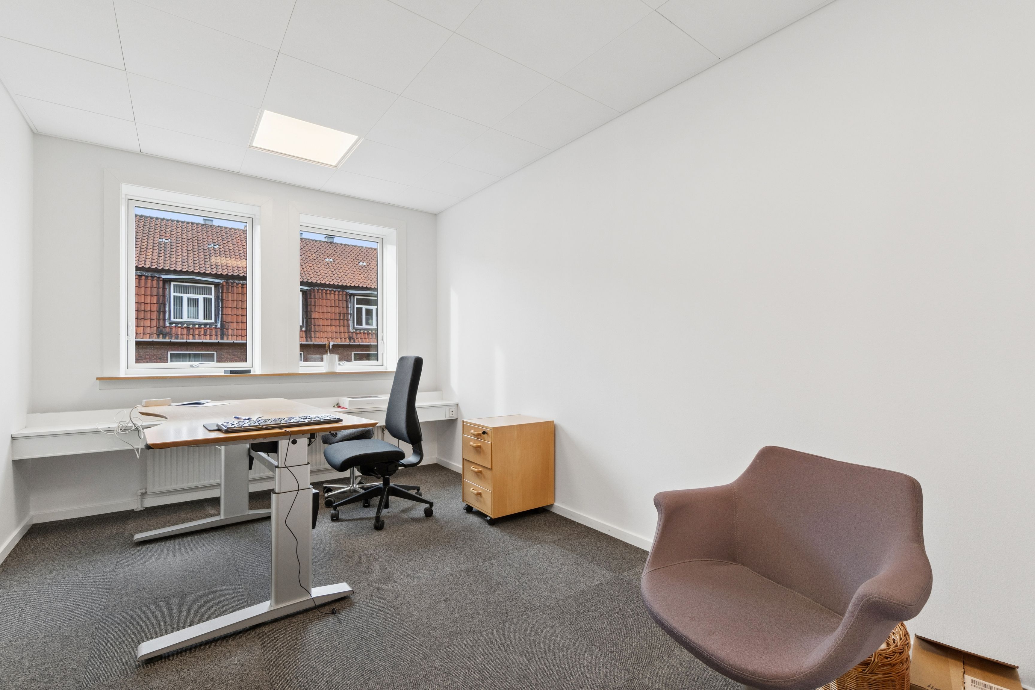 Kontorrum med højt til loftet og høj kvalitet. Et moderne skrivebord med høj kvalitet og to stole til hver stol. Et træskab med to rumme og lysekrone i loftet.