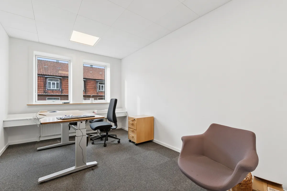 Kontorrum med højt til loftet og høj kvalitet. Et moderne skrivebord med høj kvalitet og to stole til hver stol. Et træskab med to rumme og lysekrone i loftet.