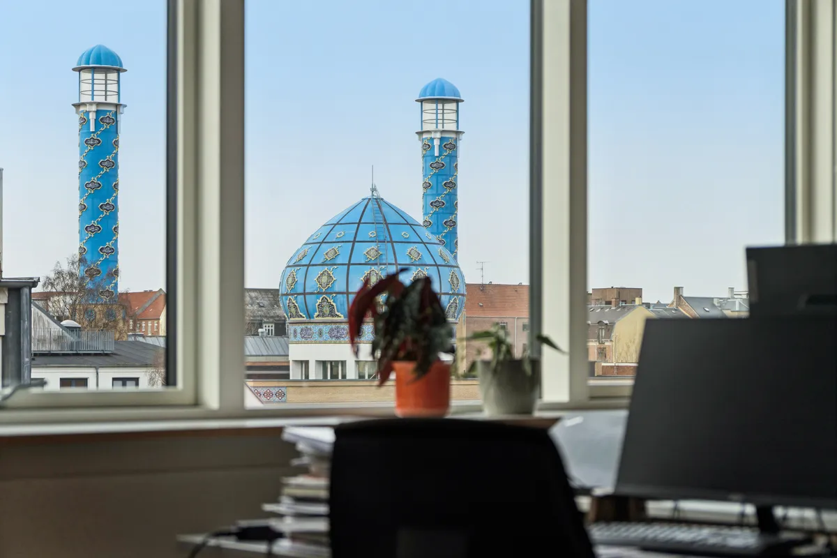 Indre kontor med udsigt til moské med kuppel og minareter, computer og grønne plantager