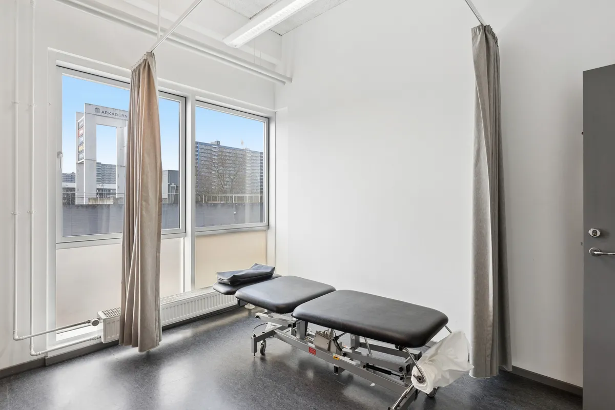 Lejlighed med to lægeborde og højt til loftet med store ruder og lysindfald fra en bygning med skrift over vinduet