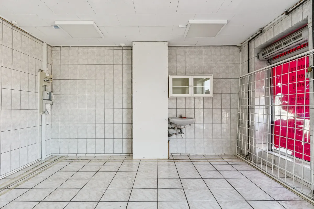 En tom lokale med hvidt loft og hvide vægge. Værelset indeholder en hvid vask og en kabinet. Lokalet er ubeboet og forsynes med luft fra et luftkanalssystem