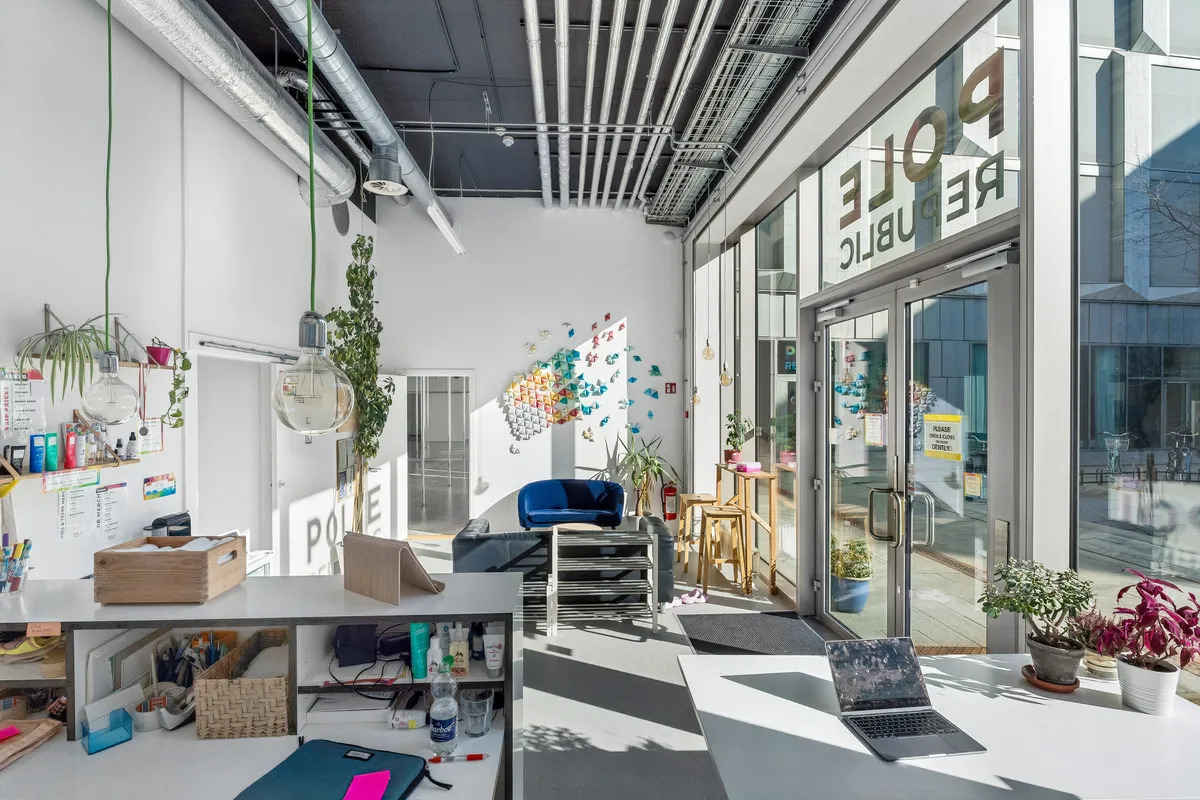 Kontor med plantepotter, en laptop og lysekroner hængende fra loftet samt væg med navnet "Polare" i store røde bogstaver.