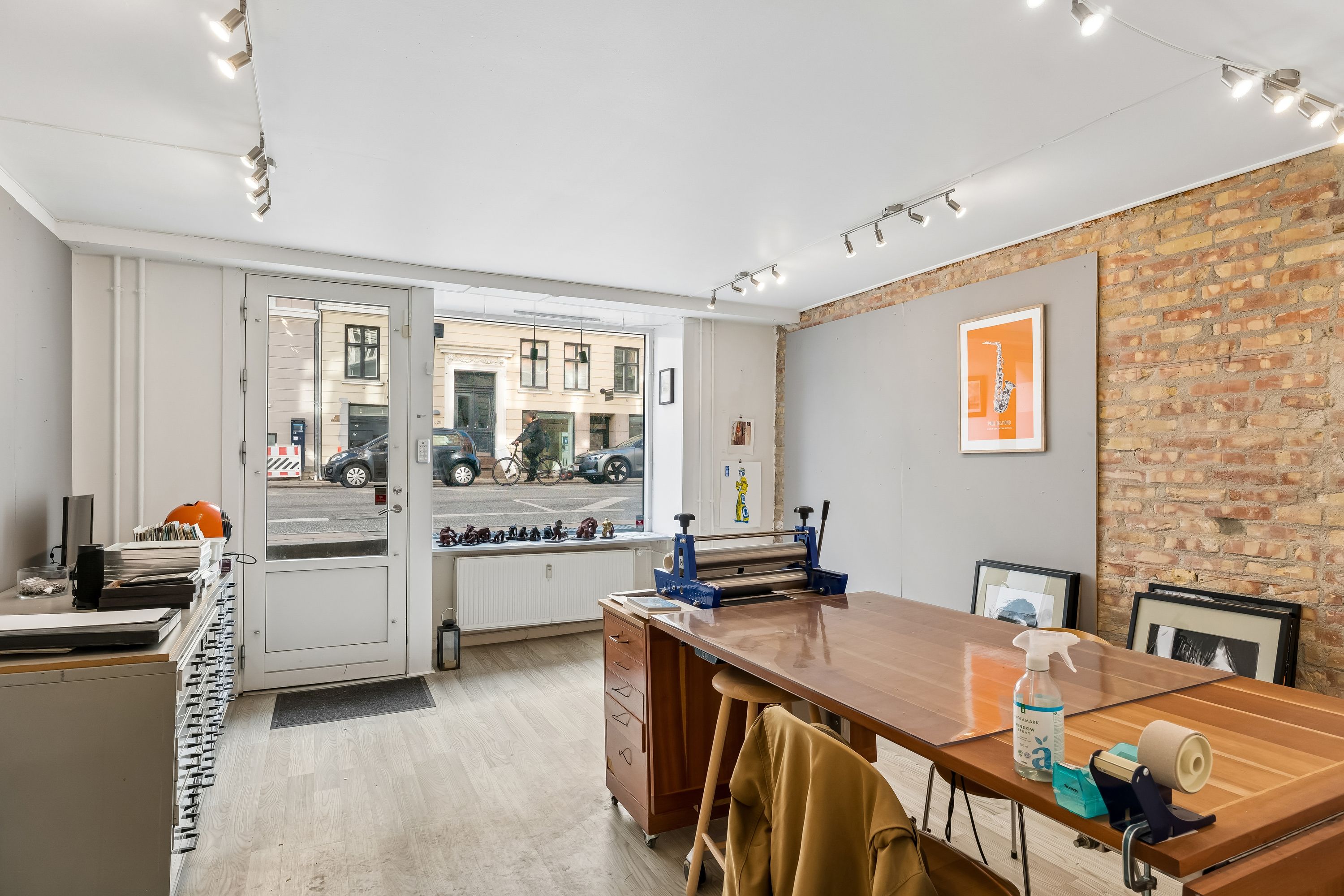 Et smukt oplyst kontorlokal med masser af lys og smukke trægulve. Et stort skrivebord og stole står klar til brug.