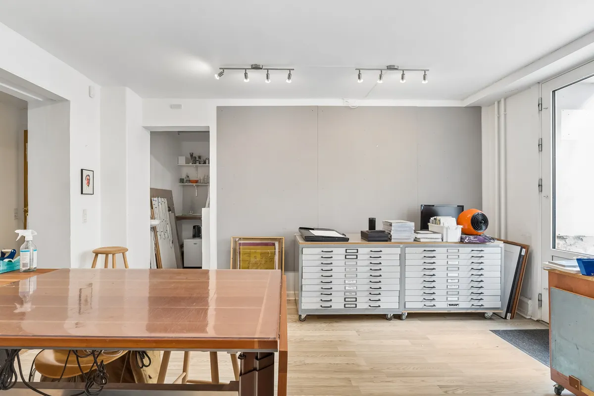 Rummelig og veludstyret erhvervslejemål med trægulv og moderne møbler. Et lagerskab med håndgribe og en stor træbord med poleret overflade.