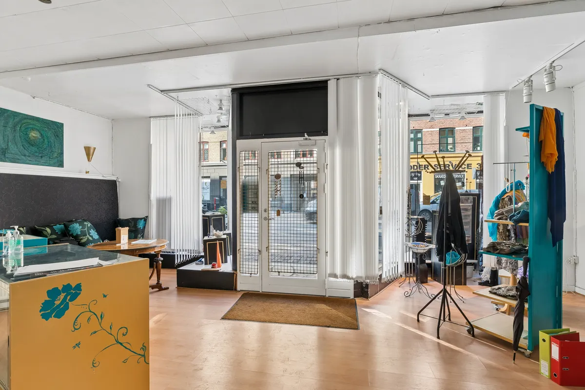 Lejlighedsbutik med sofa, bord og klædeskab med tøj og paraplyer og gulvbelægning i træ