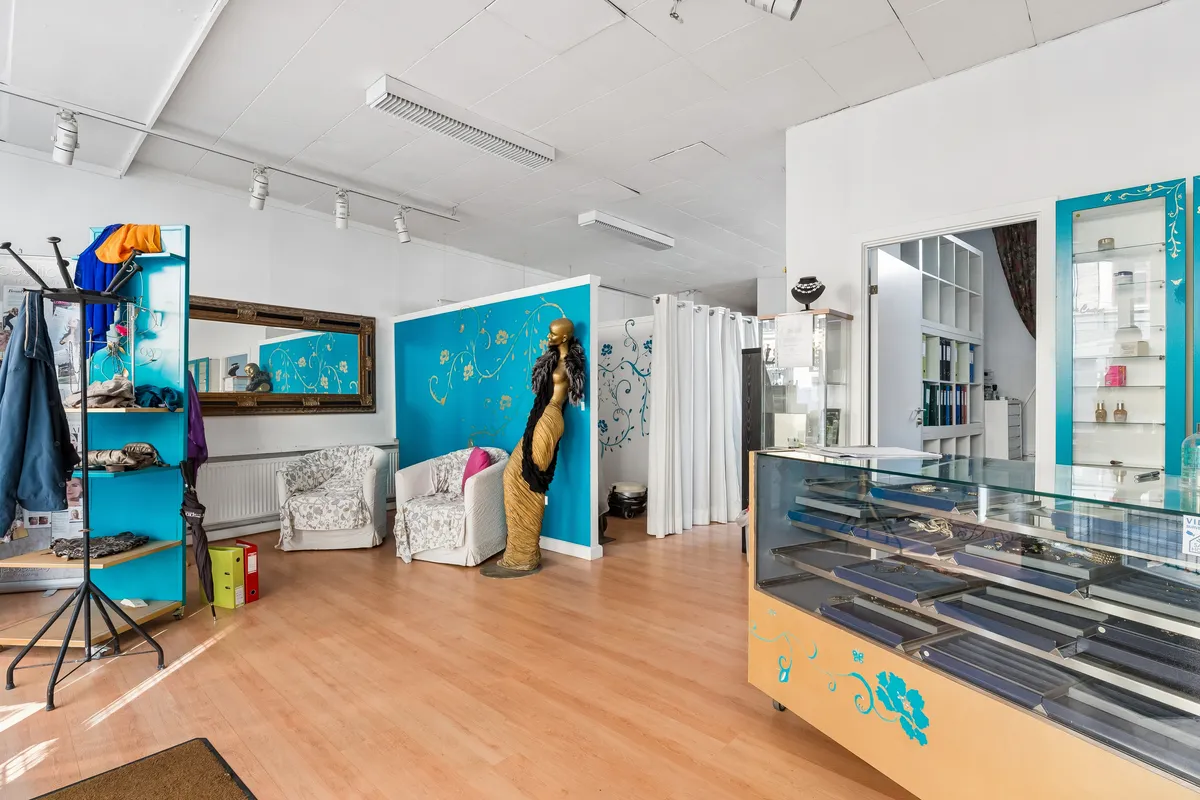 Københavnsk butikslokale med lysegul gulv, lyseblå vægge og møbler, samt en guldvæsentlig statue og flere butiksreoler med eksempler på smykker