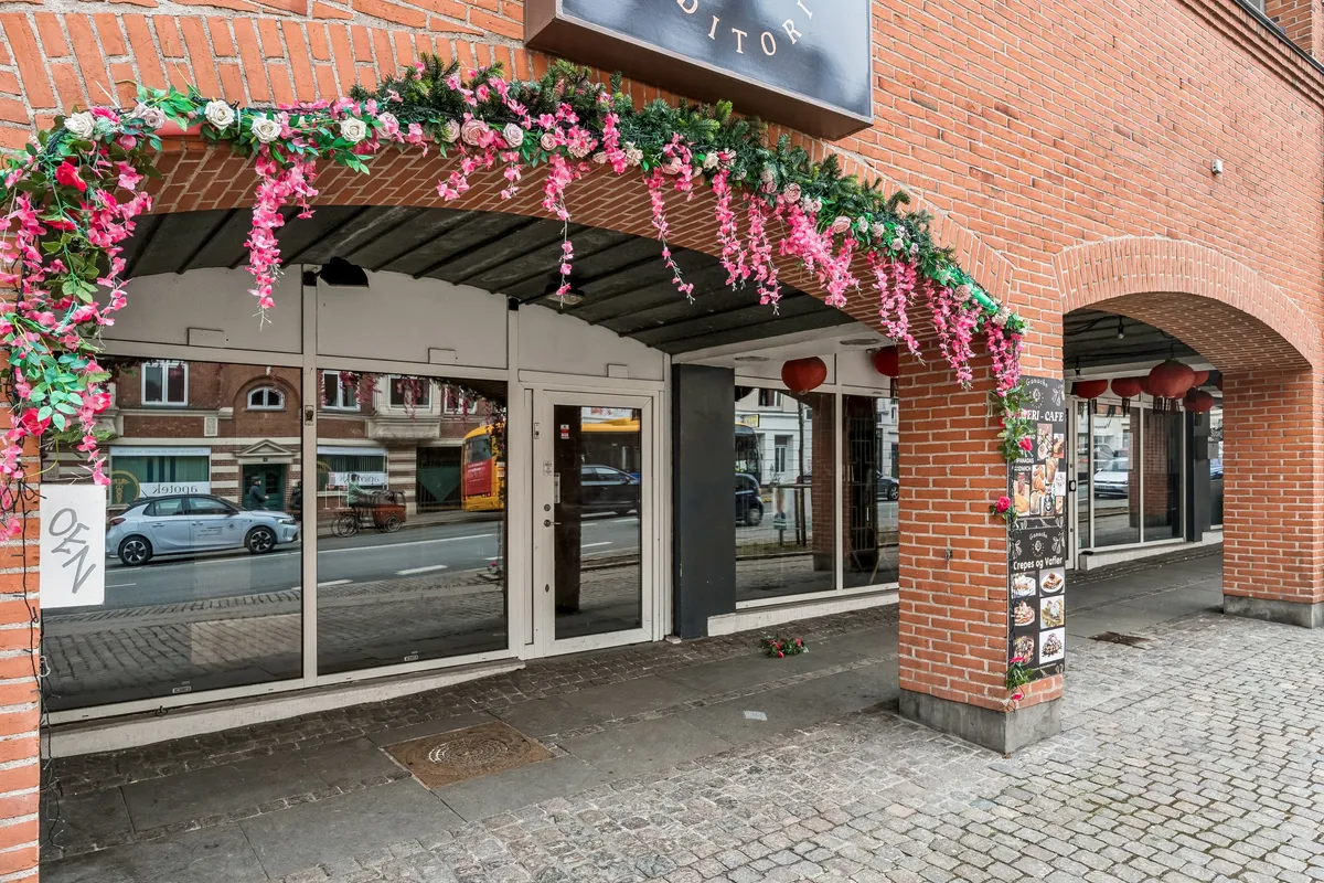 Rød mursten med blomsterbuket over indgangsdør og skilt med teksten "ditof" i hvidt. Hængende røde lanterner og skilt med opskrifter på crepes og vafler