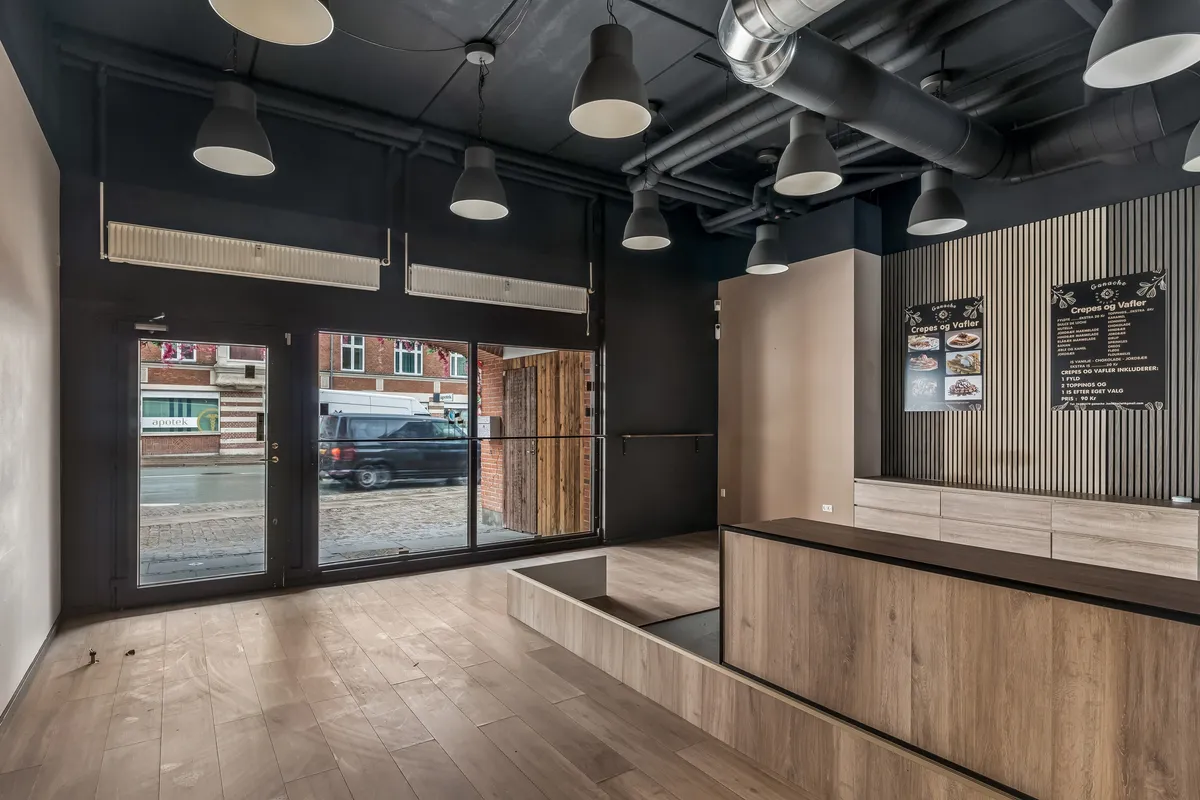 Lejlighed til leje i Valby med moderne indretning, åbne glasdøre og en elegant kontorbar med træelementer og lyse blyanter i loftet.