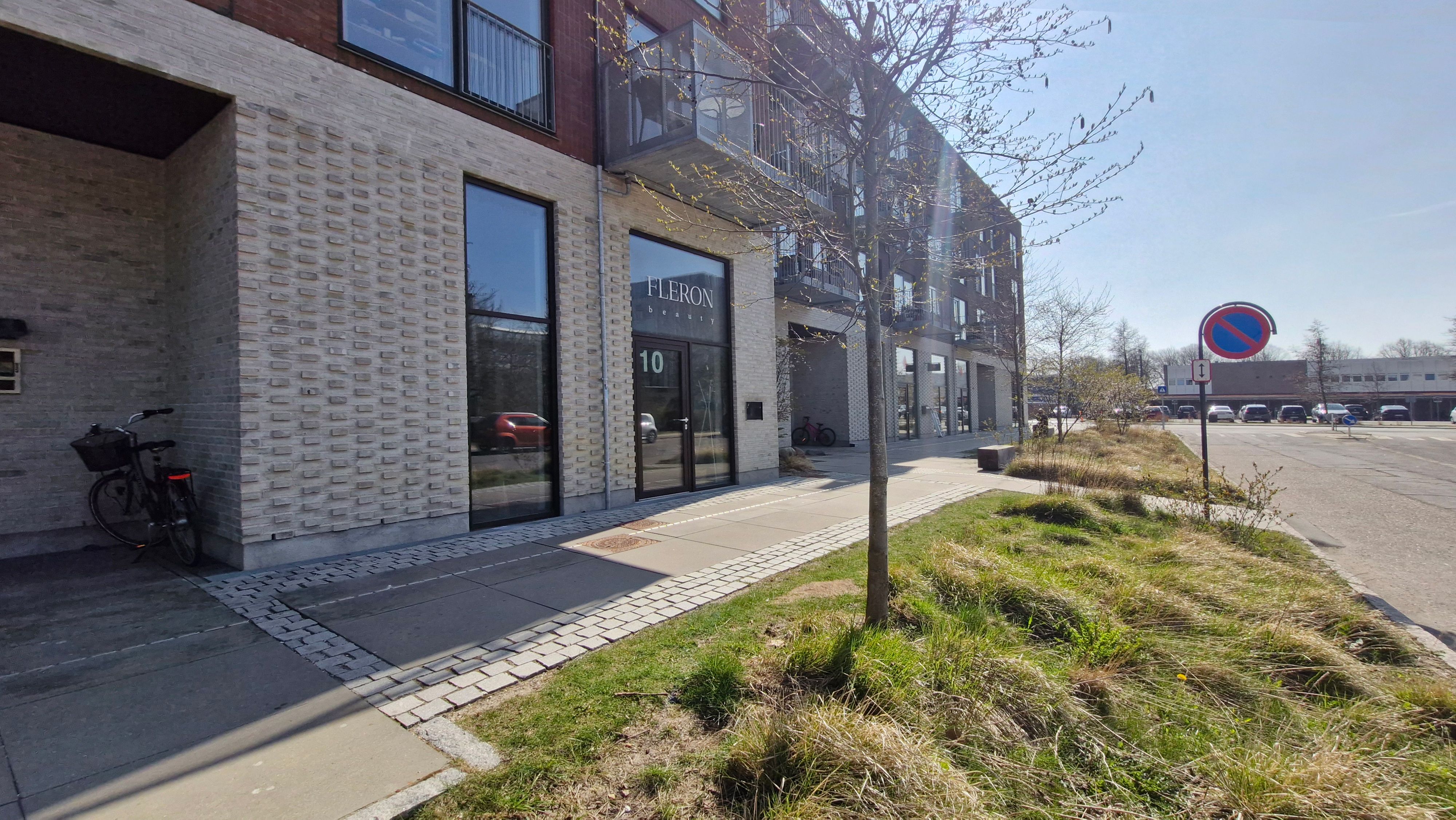 Kontorlejemål på Næsbyvej 10 i Rødovre med store vinduer og terrasser, en cykel parkeret og græsser i forgrunden og en tydelig schild med nummeret 10 på bygningen