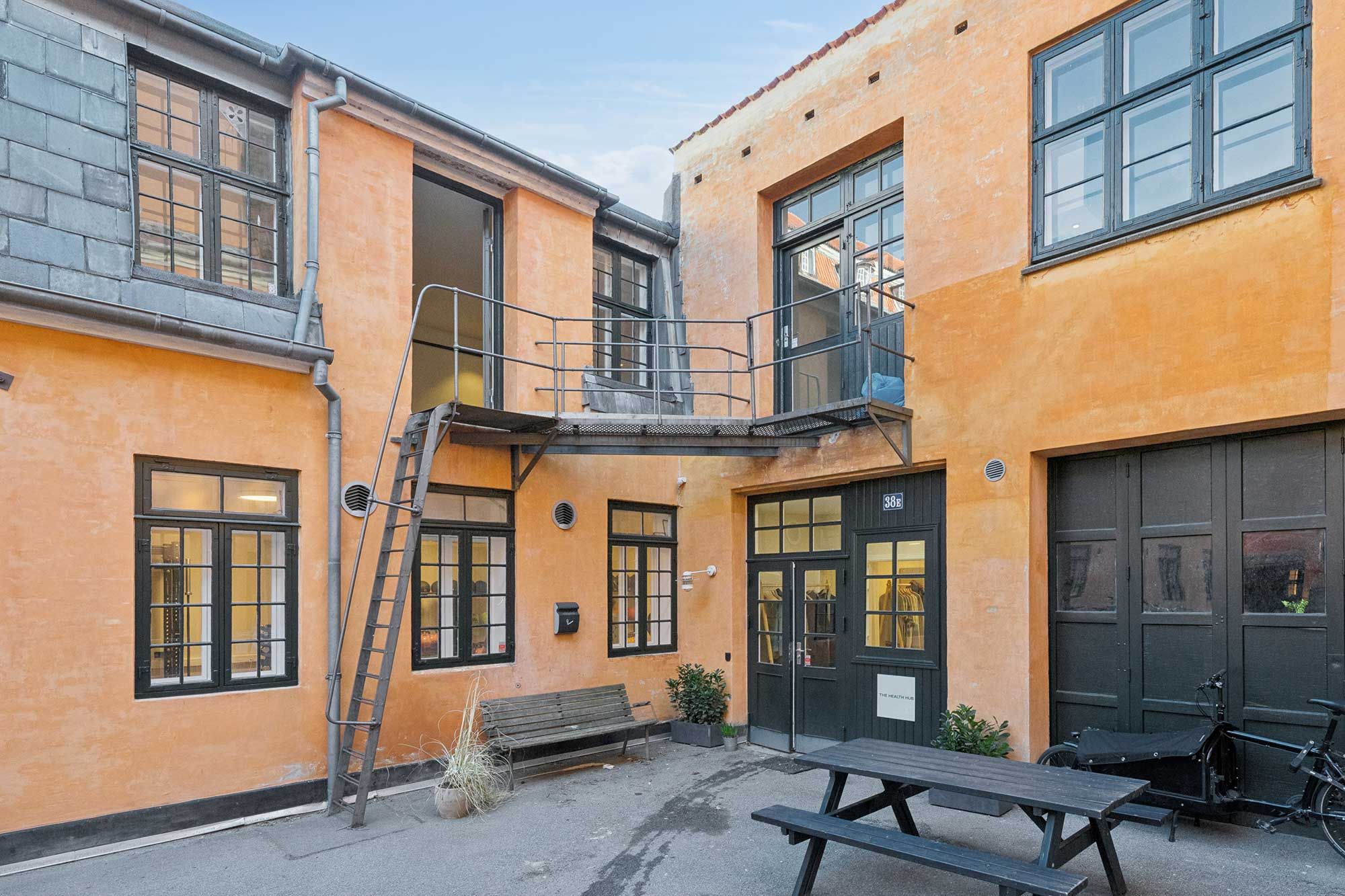 Moderne kontorlejemål med terrasse og trappe i Indre By. Kontorlejlighed med lyse gulve og store ruder. Smukt gårdmiljø med grønne planter og parkeringsplads.