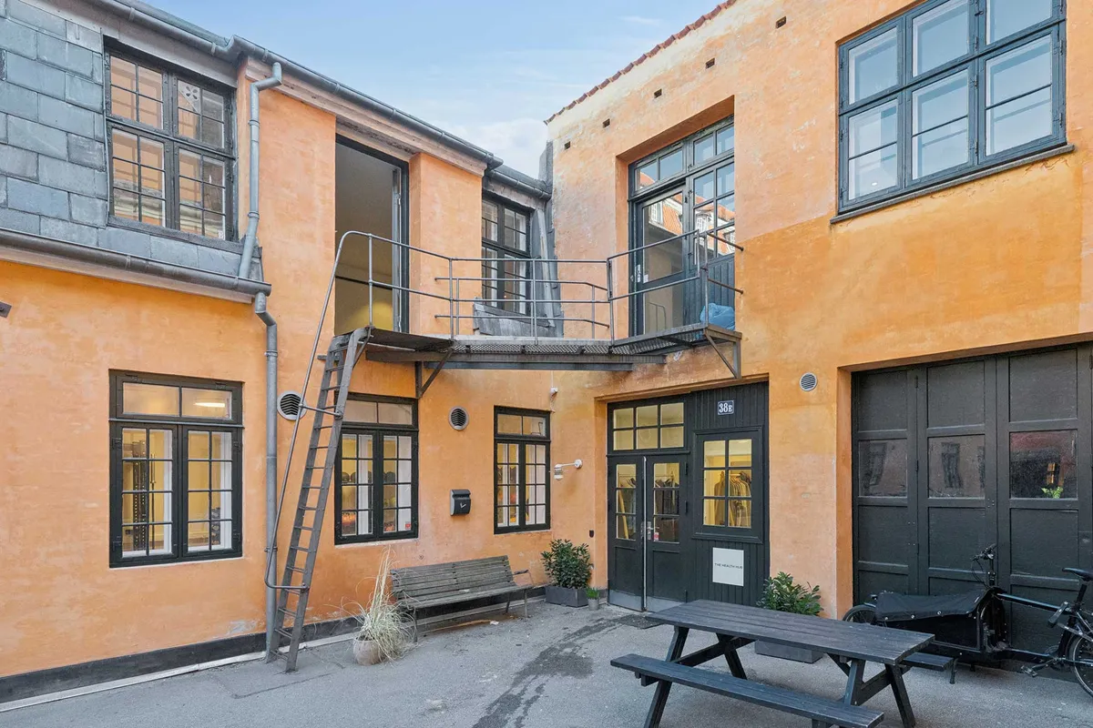 Moderne kontorlejemål med terrasse og trappe i Indre By. Kontorlejlighed med lyse gulve og store ruder. Smukt gårdmiljø med grønne planter og parkeringsplads.