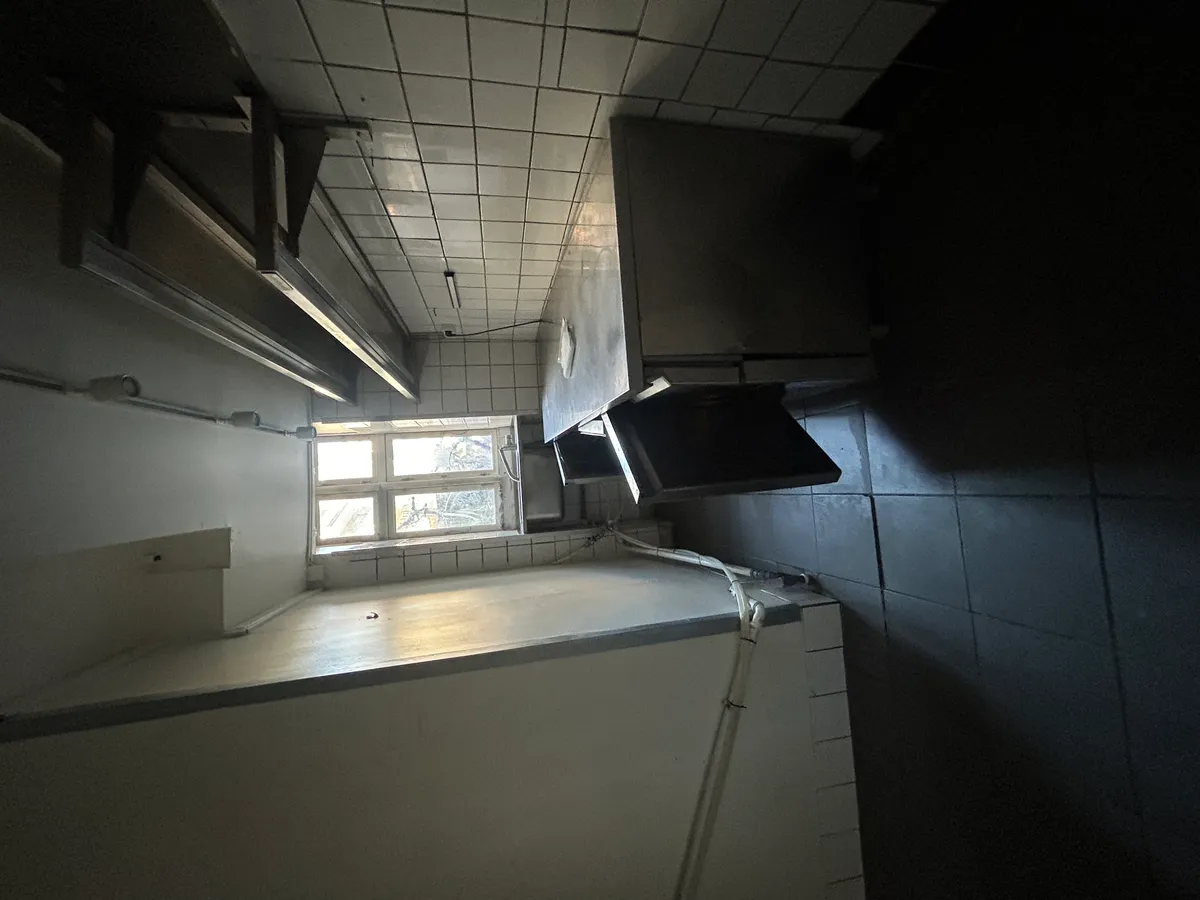 Take-away med industriudsugning og køkkenudstyret. Vinduet er åbent, og der er et højt loft med hvidt fliseloft.