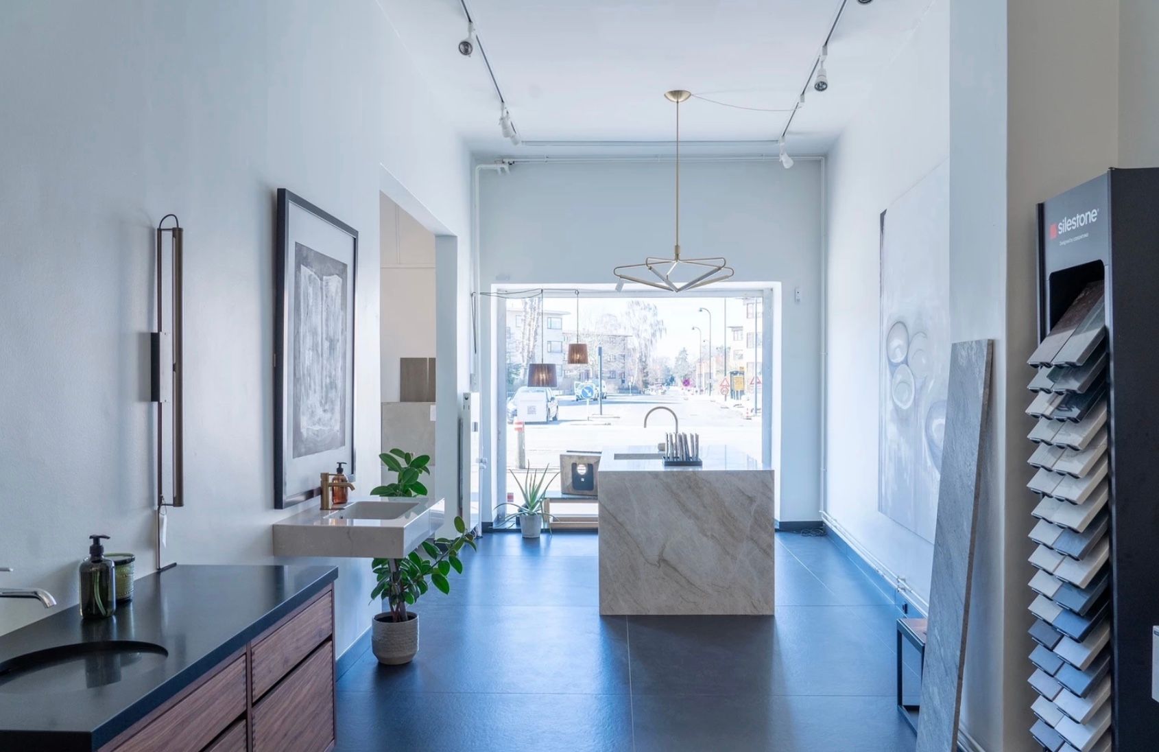 Billede af nyrenoveret butik med marmorgulve og lyse loftslampe. I baggrunden er en udsigt til en gård og grønne områder.