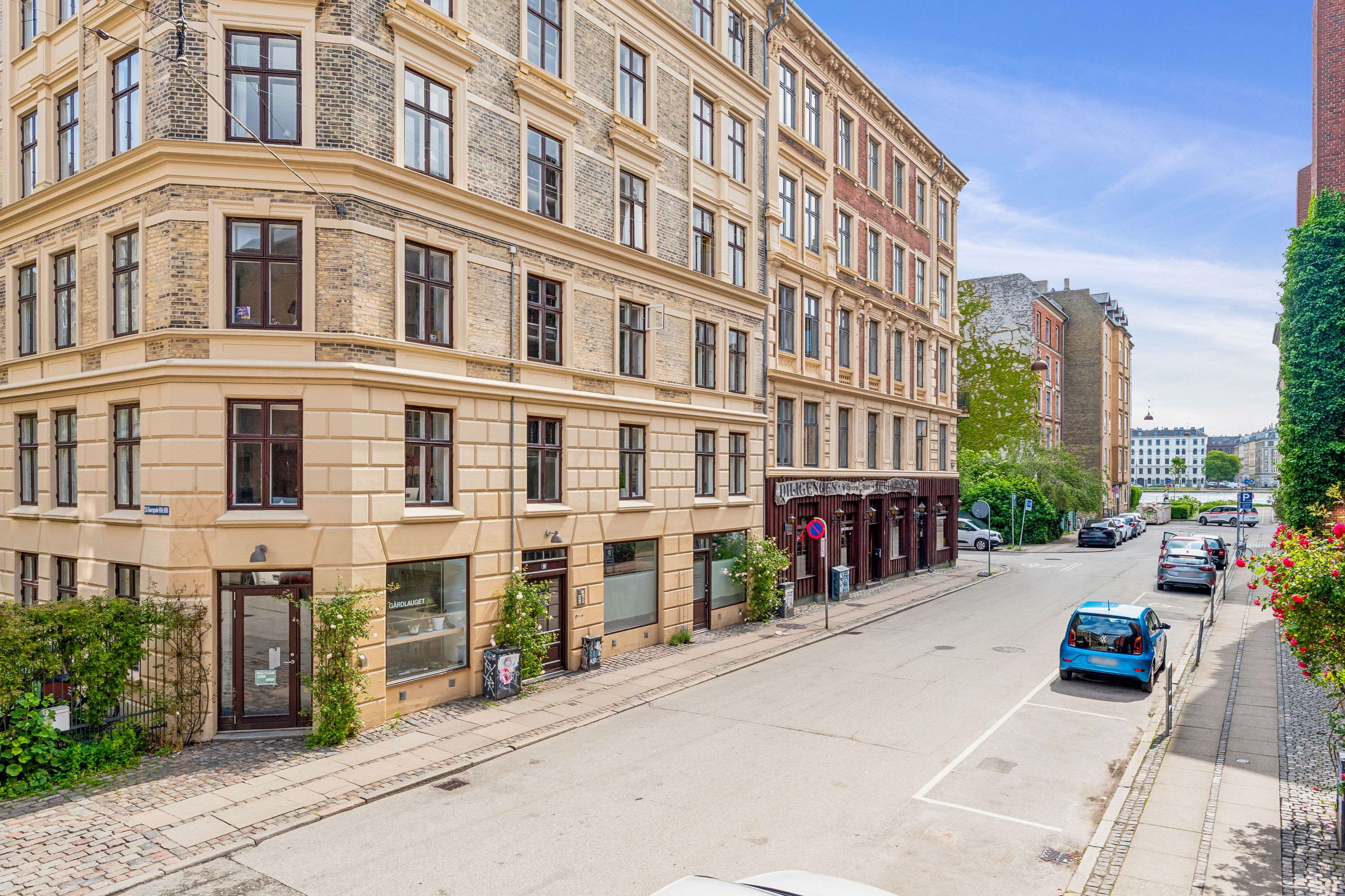 Korsgade i København med en stor bygning, der er udsmykket med mange vinduer og et glasdækket butiksvindue