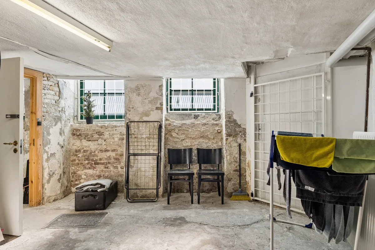 Kontor til salg i stueplan med fin kælder, 2 stole, tørretøjsstativ og grønt plante. Enheden er registreret som kontor og har mulighed for erhvervsandel