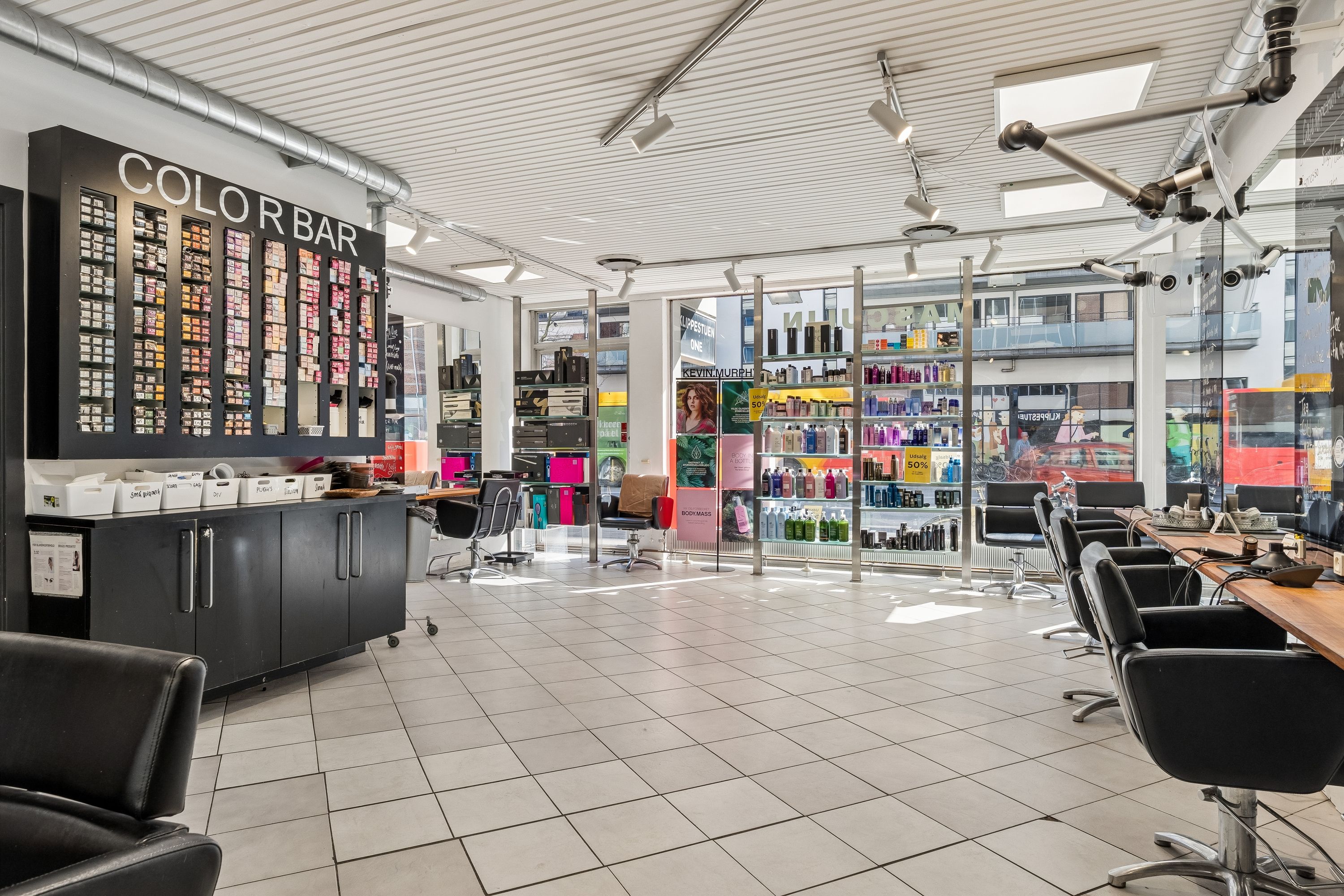 Køb denne frisørsalon på H.C. Ørsteds Vej 1B med lyse lofter og gulv. Sorte stole, røde barberskærere og farverige vægge. Butikken er forberedt til ny brug.