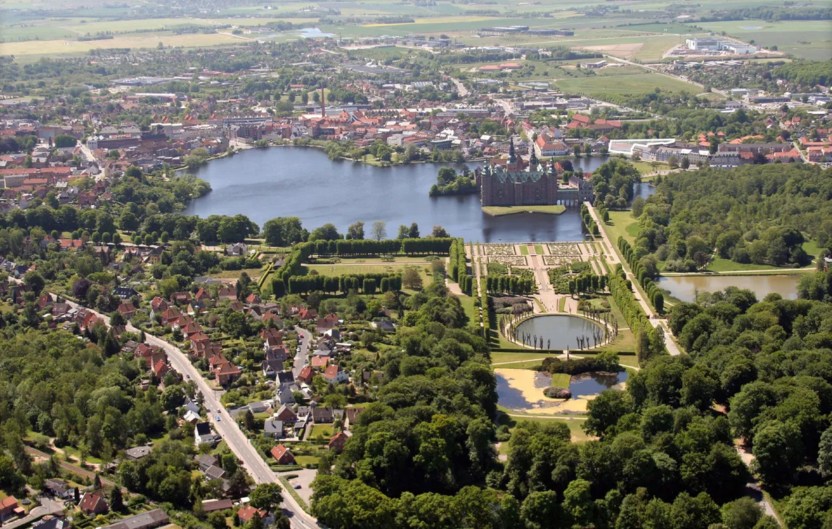 Billede af Frederiksborg Slot med Frederiksborg Slotpark og en smuk sø i Hillerød med bygninger og veje rundt omkring