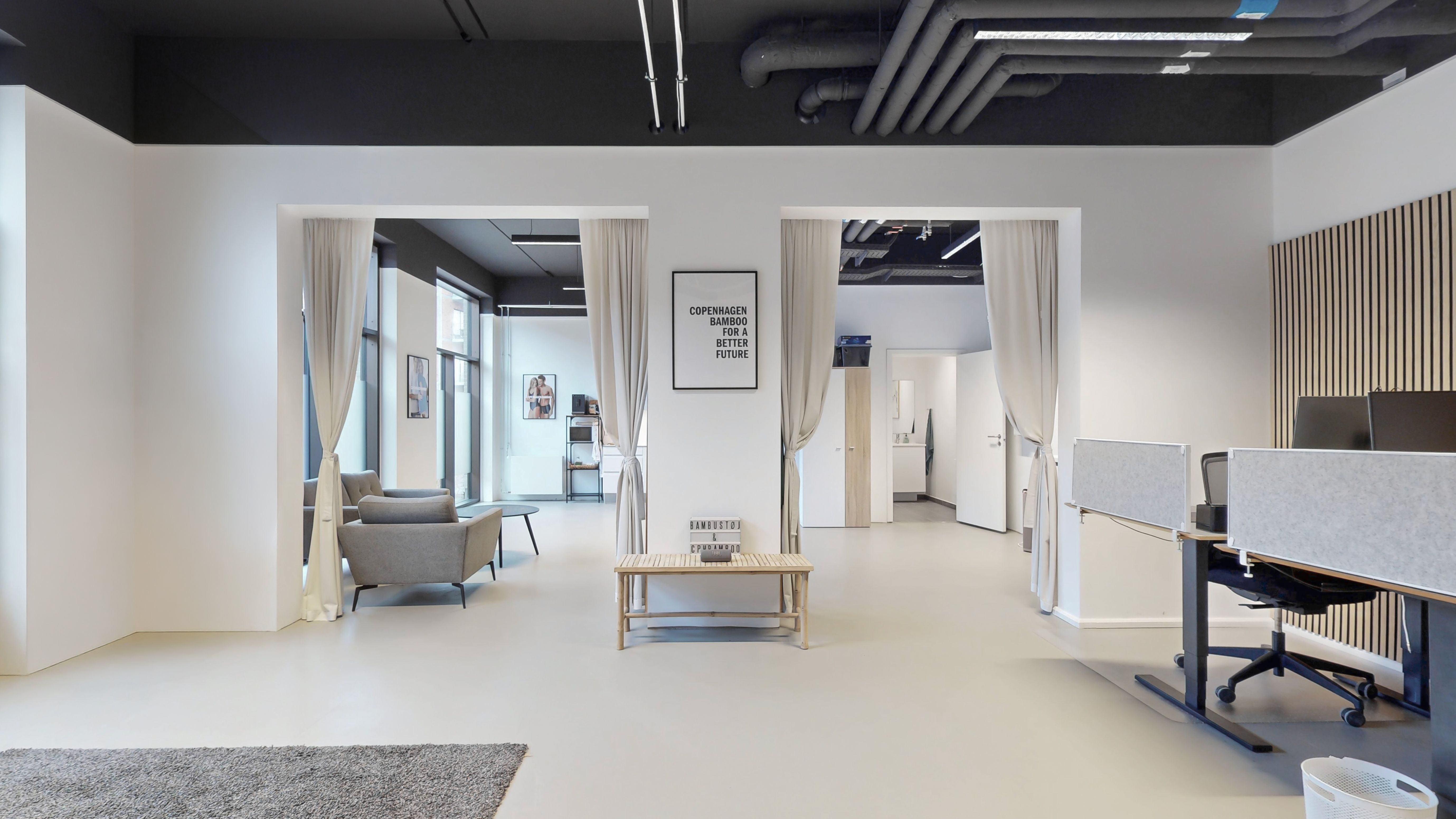 Lyst og moderne kontorlokale med hvide vægge og mørkt loft. Værelse med moderne møbler, skrivebord og stole. Dekorative elementer og tekster på væggen.