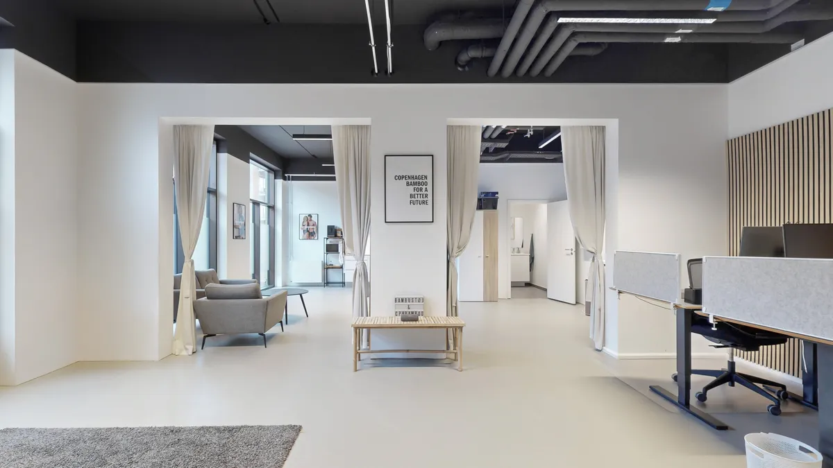 Lyst og moderne kontorlokale med hvide vægge og mørkt loft. Værelse med moderne møbler, skrivebord og stole. Dekorative elementer og tekster på væggen.