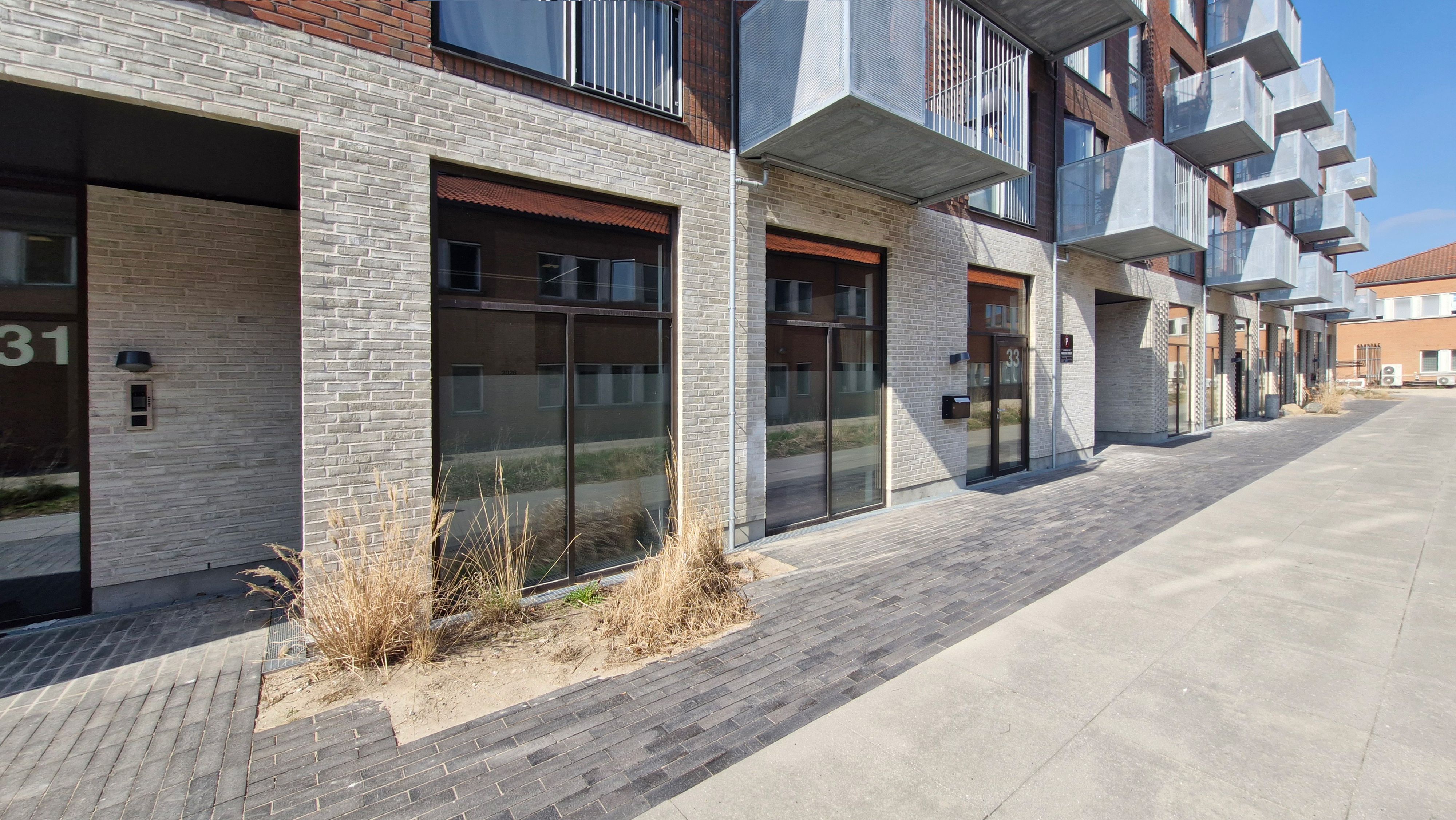 Moderne kontorbygning med glasvinduer og trapper til leje i Rødovre. Knægt og terrasser. Adresse 33 og nummerplade.