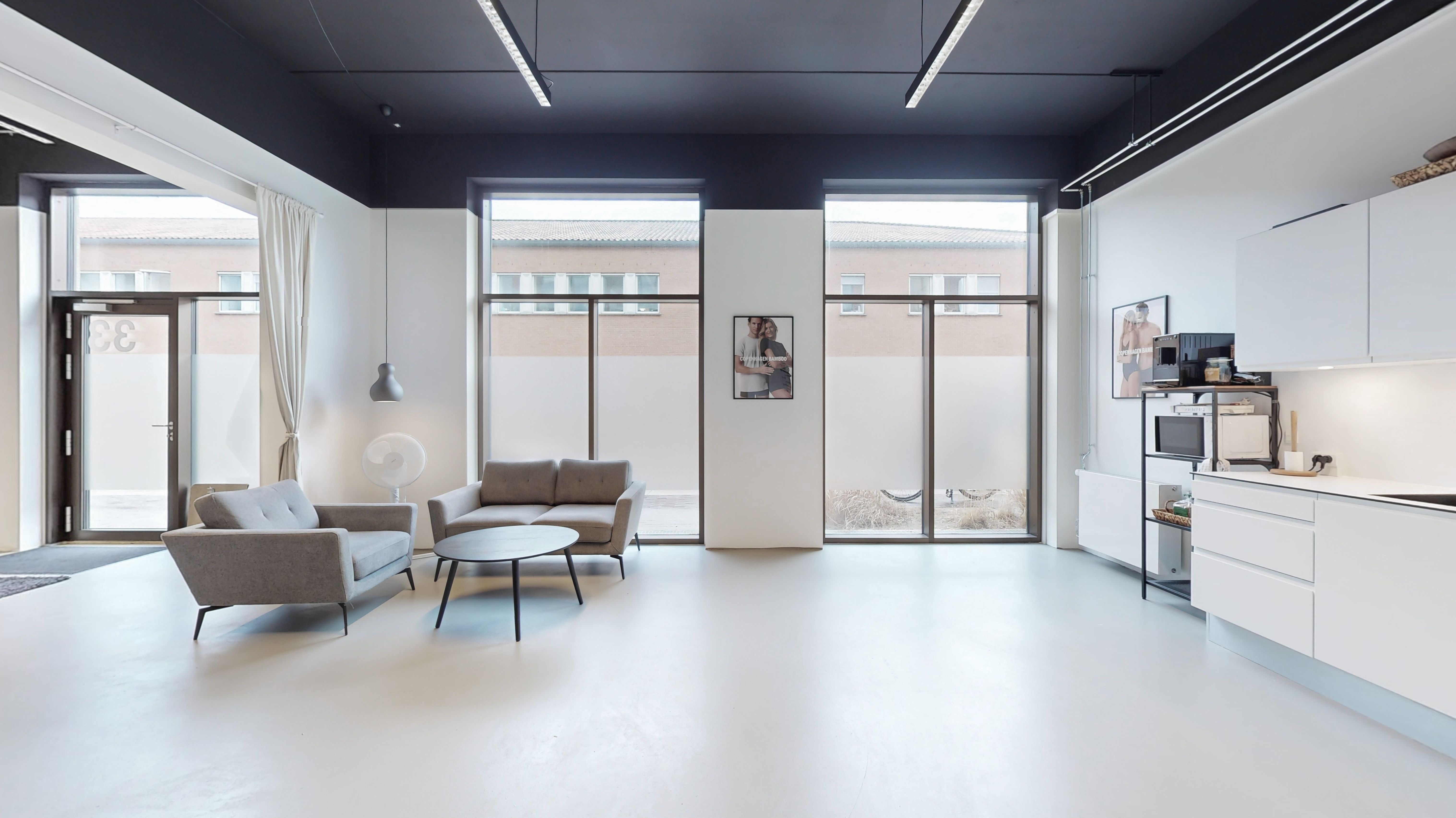 Kontorlokale med hvide vægge, mørkt loft, moderne møbler, store ruder og smukke udsigt.