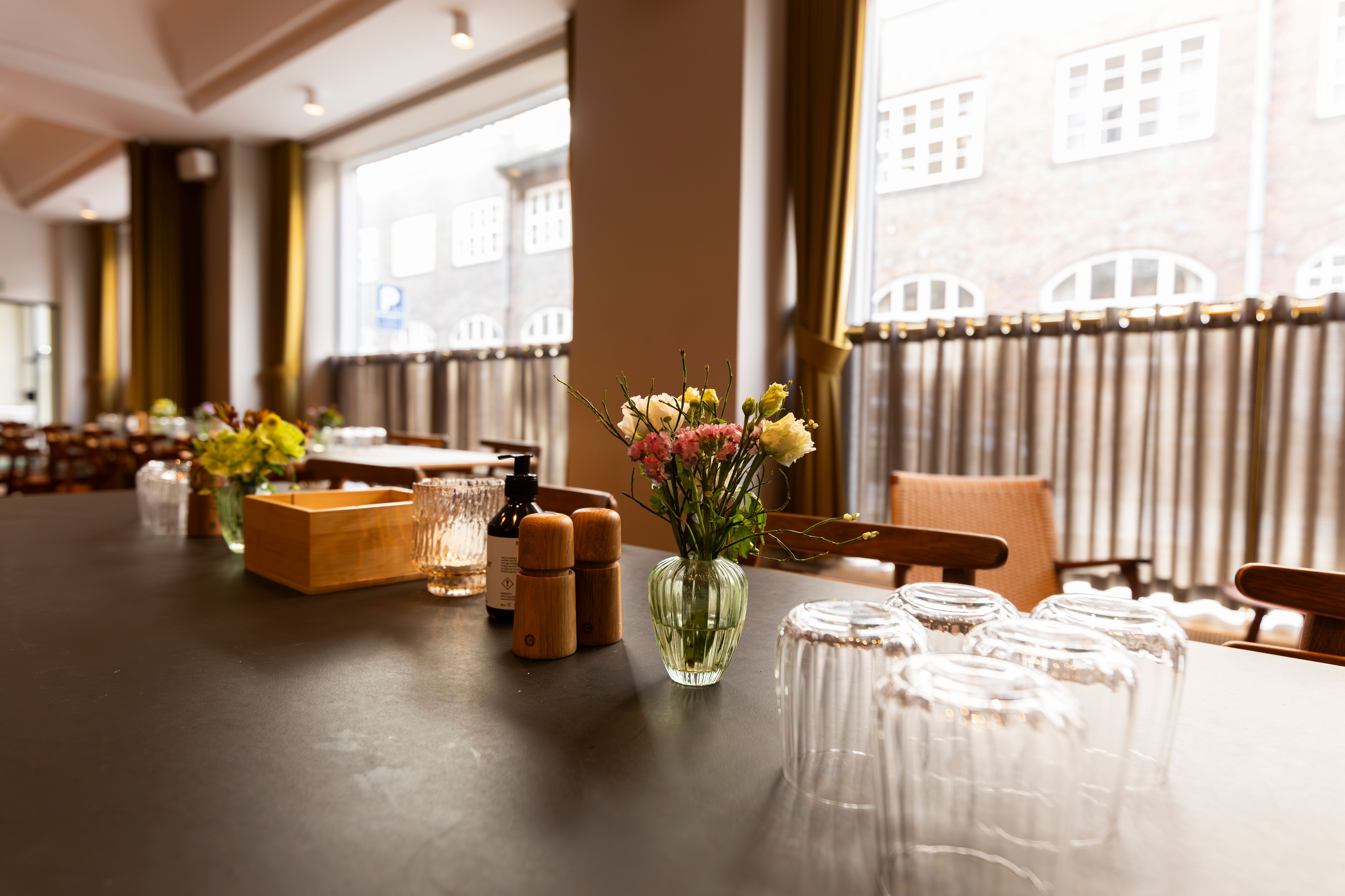 Elegant kontor med udsigt til Kongens Have, møbler og dekorationer i lyse farver, vinduer med mønstrede gardiner, en væskeflaske og salt og peber.