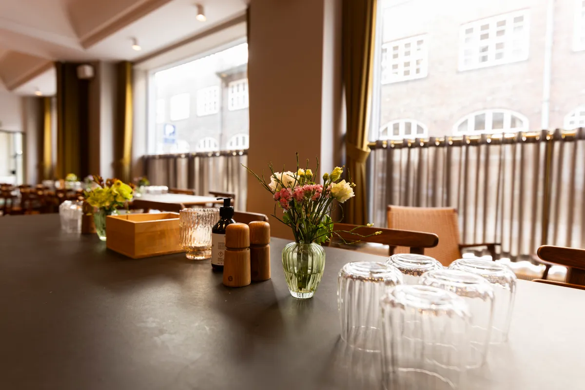 Elegant kontor med udsigt til Kongens Have, møbler og dekorationer i lyse farver, vinduer med mønstrede gardiner, en væskeflaske og salt og peber.