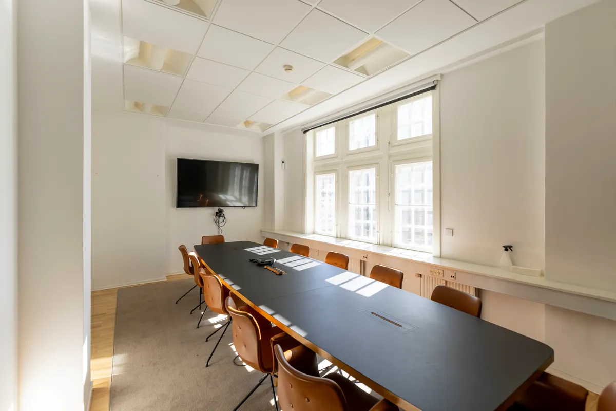 Ny kontor med lyse tage, tv, vinduer og borde samt stole med skinnende lædermøbler i lyse farver