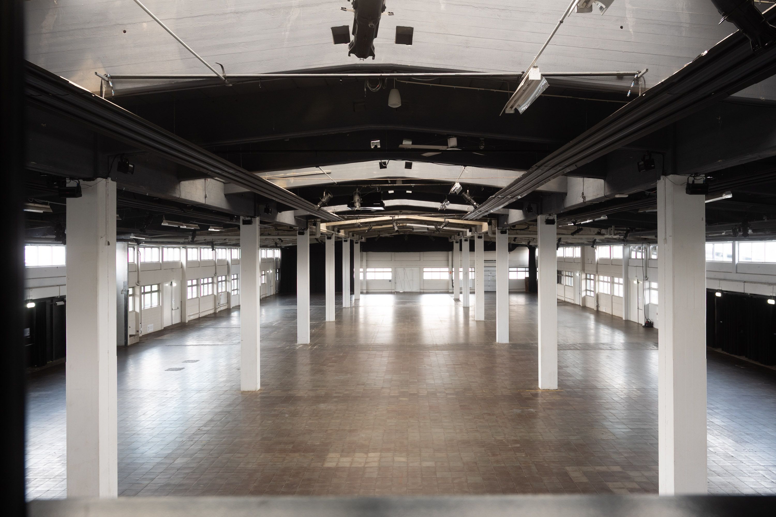 Indvendigt af et stort kontor med lyse lofter, høje søjler, en betongulv og vinduer med lysegardiner