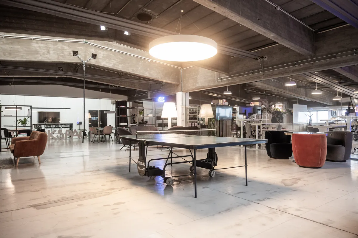 Kontor med pingpongbord, møbler, tv og lyskabler på loftet, for at skabe et hyggeligt arbejdsmiljø i kontorlokaler
