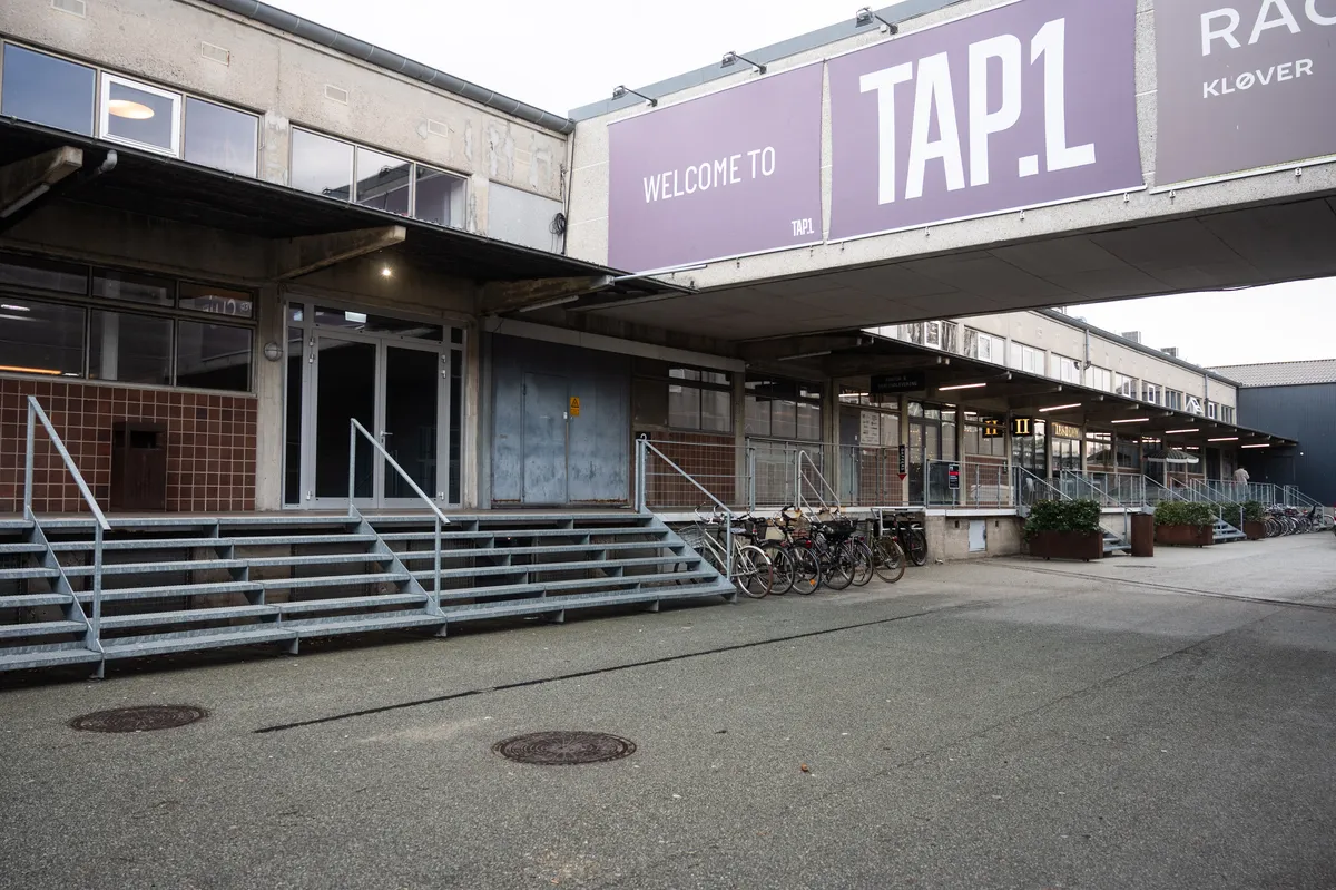 Udenfor er der et kontorbygger med skriften Welcome to Tap1 på facaden og flere cykler parkeret foran